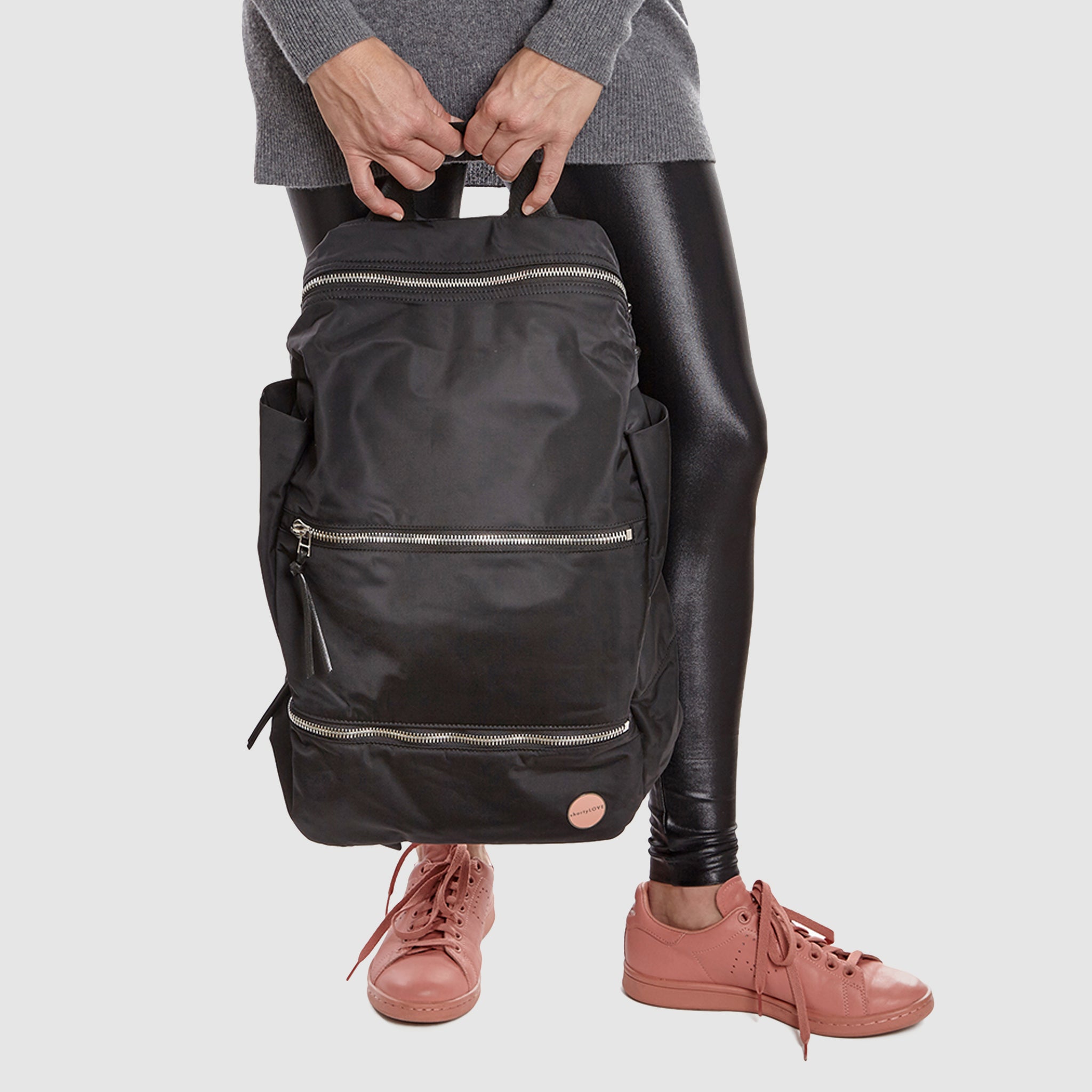 shortyLOVE boxer backpack bag in black; held in hand by model in grey sweater and black leggings against white background.