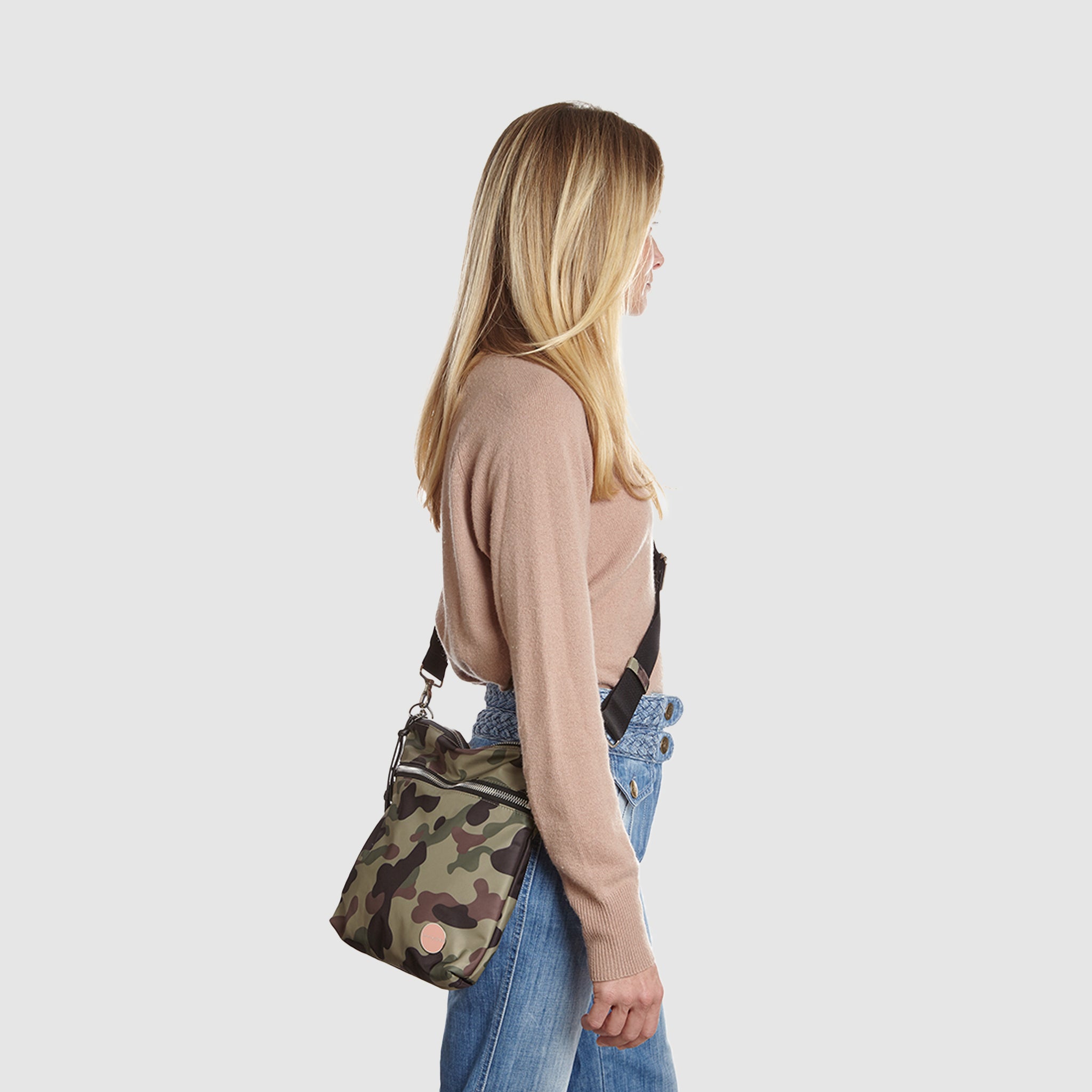 shortyLOVE amuse medium sized crossbody bag in green camo; on model in tan v-neck long sleeve sweater and jeans against white background.