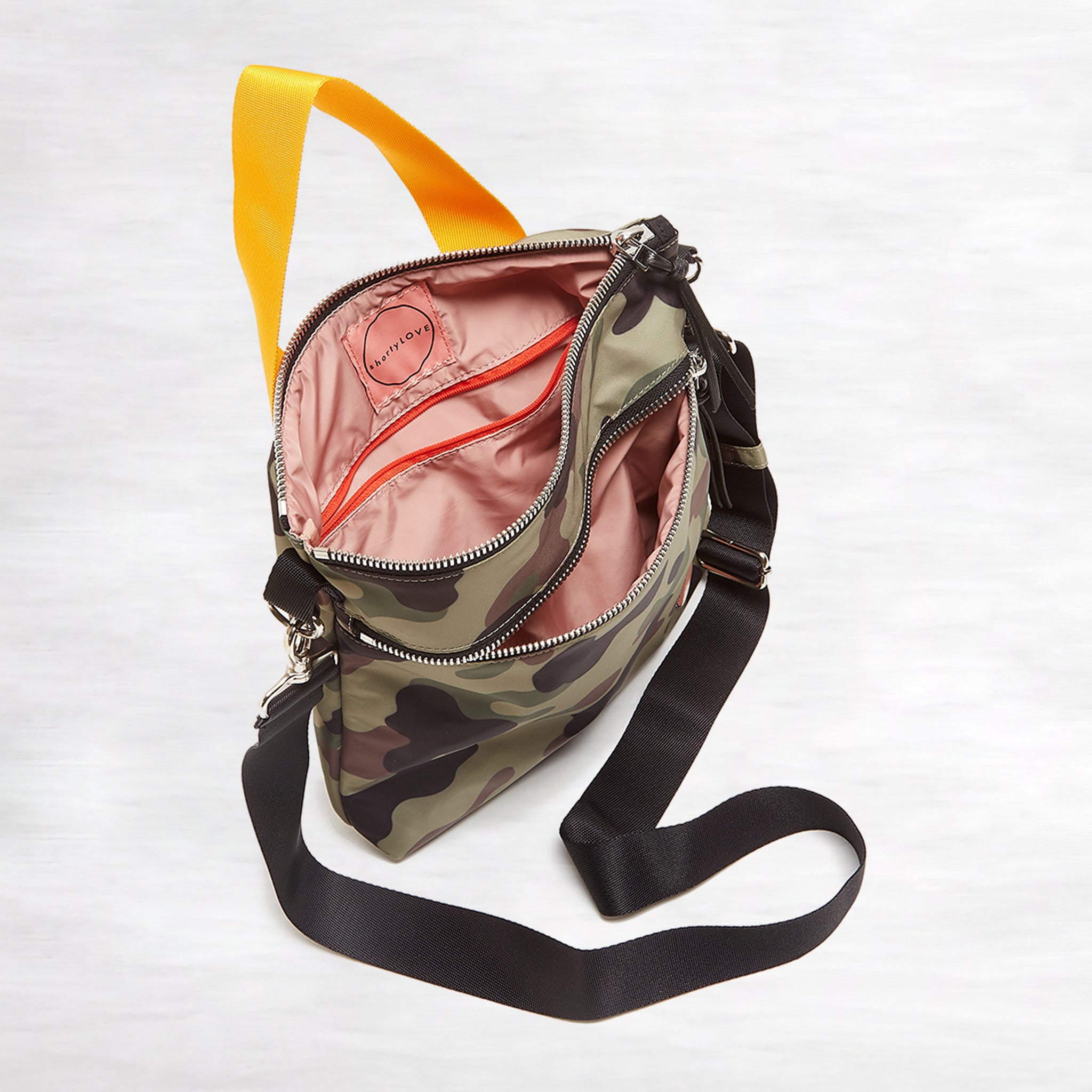 shortyLOVE amuse medium sized crossbody bag in green camo; top-down view showing interior pink lining against white background.