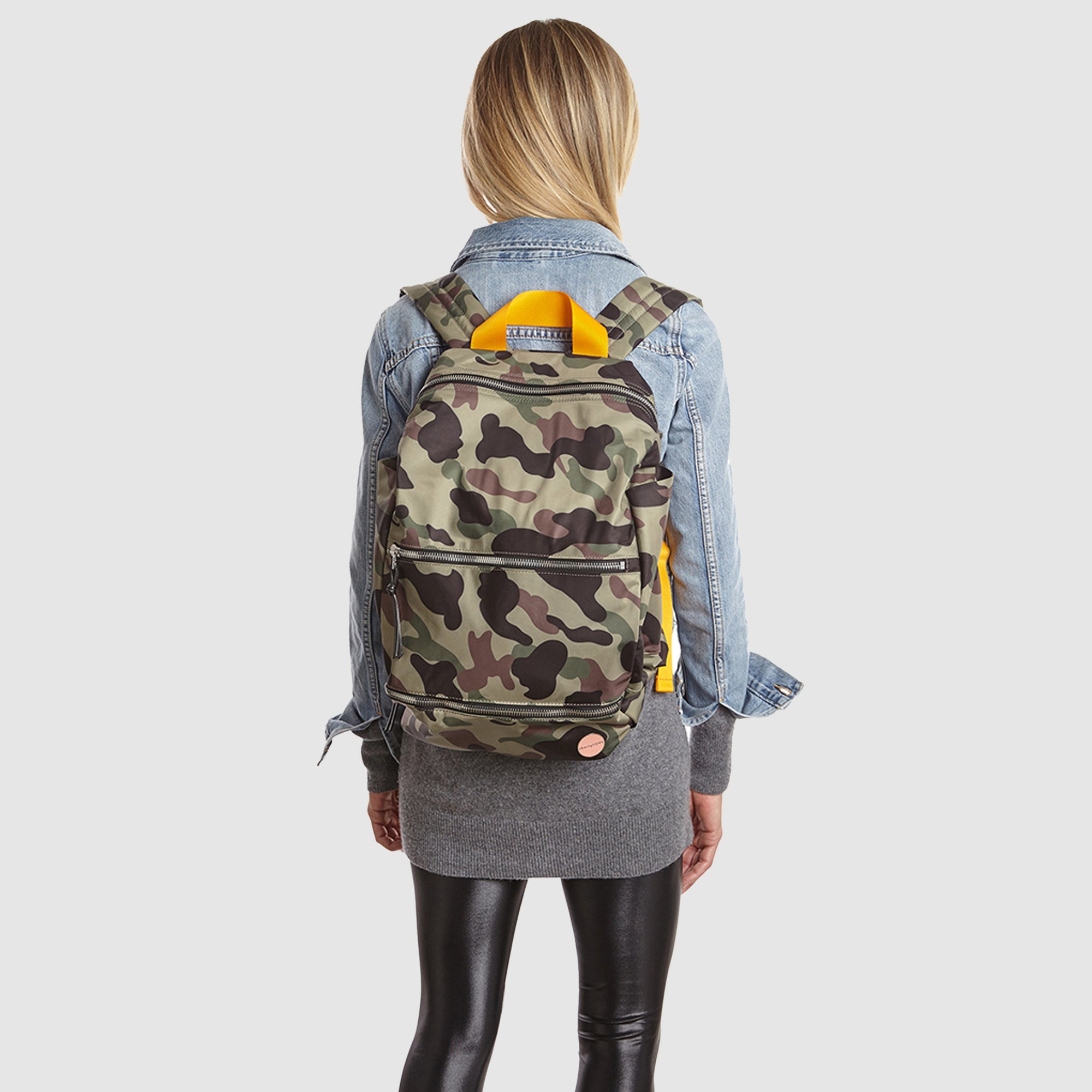 shortyLOVE boxer backpack bag in green camo; on model in blue jean jacket and black leggings against white background.