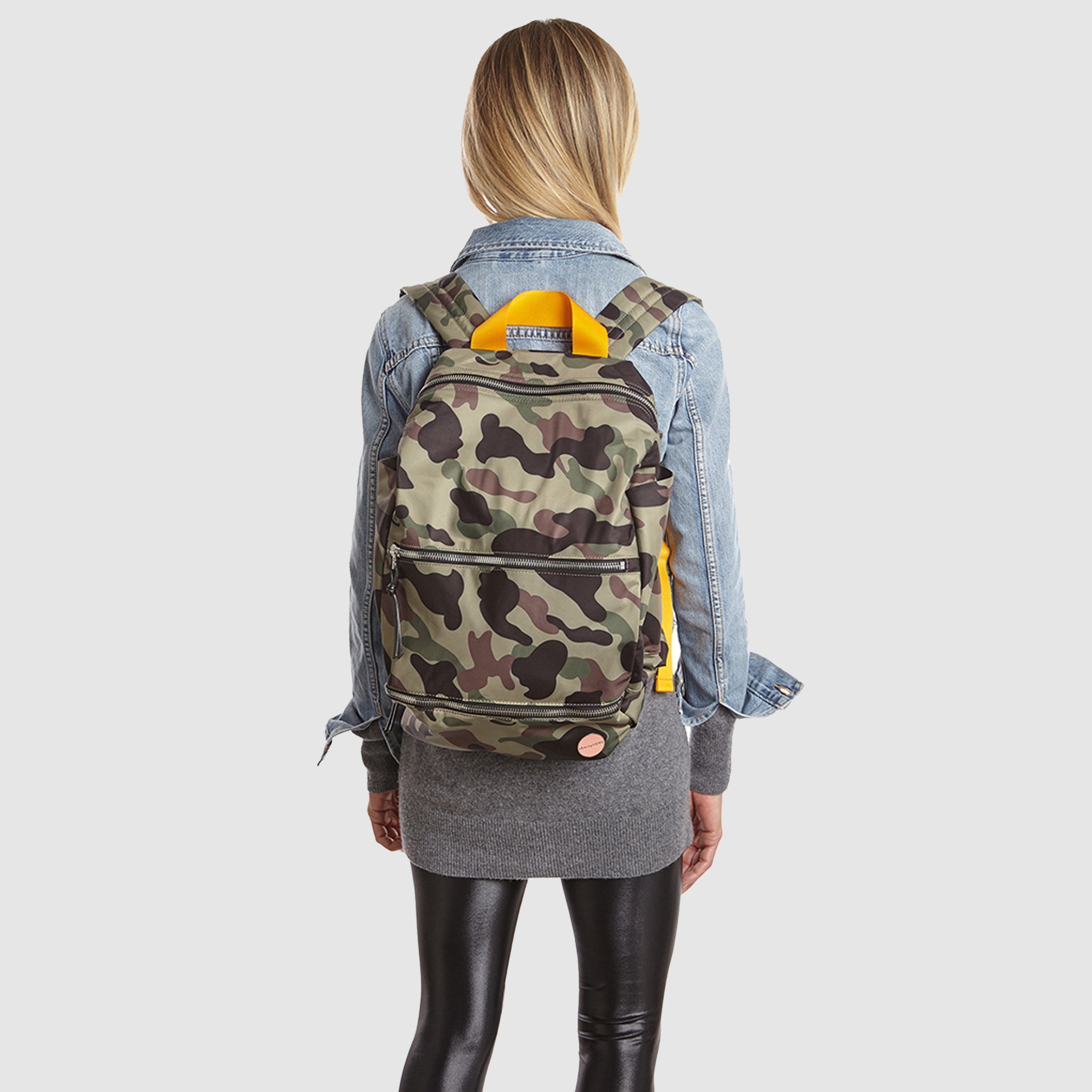 shortyLOVE boxer backpack bag in green camo; on model in blue jean jacket and black leggings against white background.