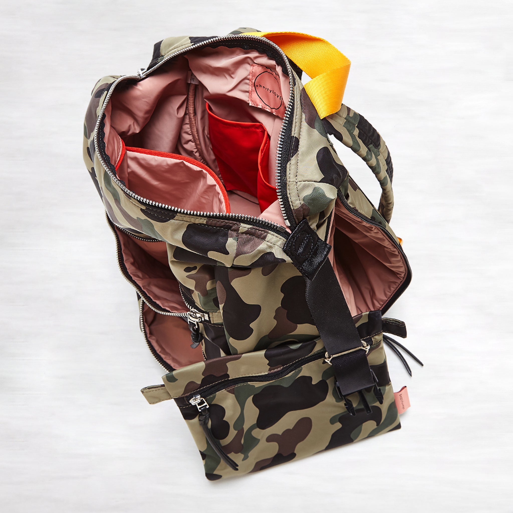 shortyLOVE boxer backpack bag in green camo; top-down view showing interior pink lining against white background.