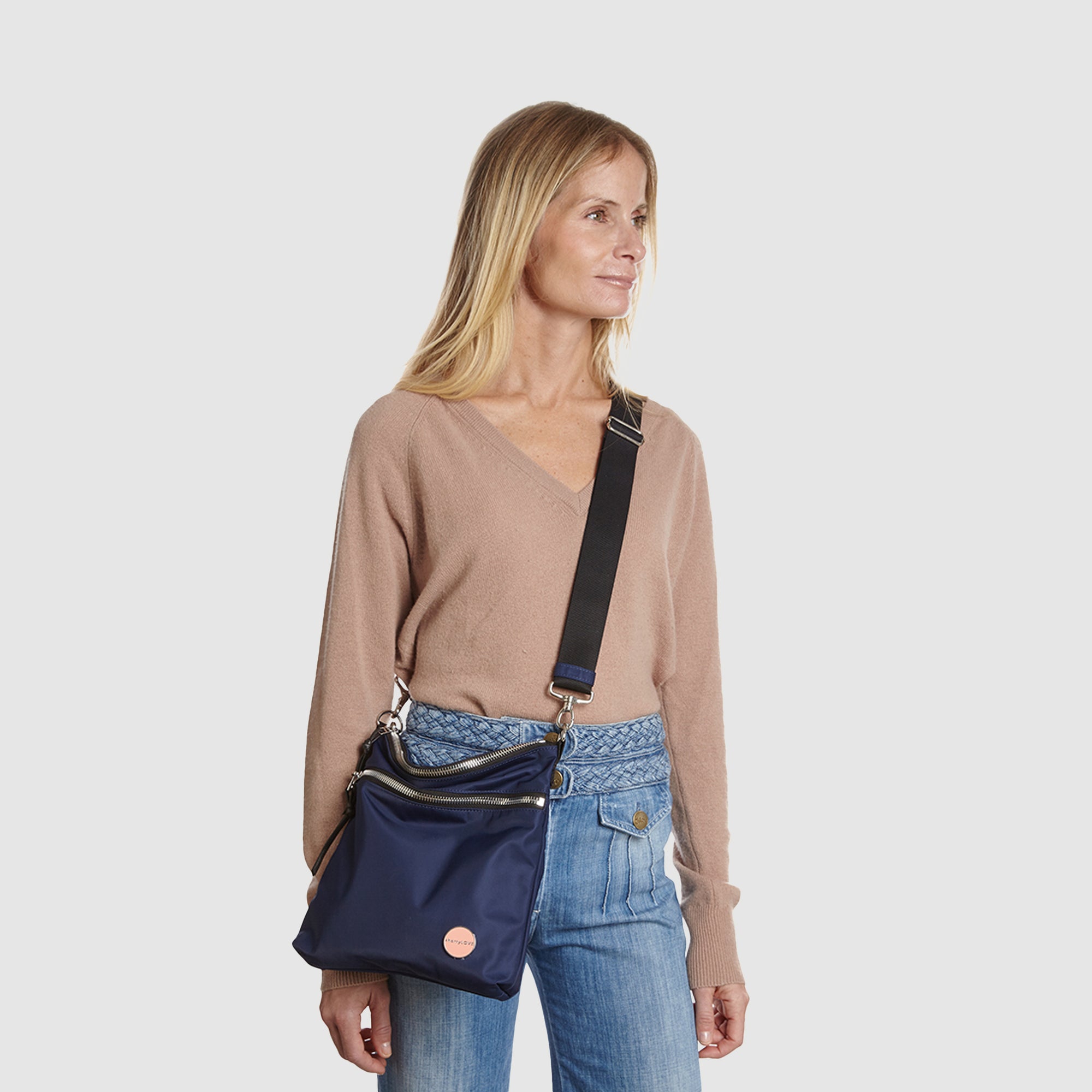 shortyLOVE amuse medium sized crossbody bag in navy; on model in tan v-neck long sleeve sweater and jeans against white background.
