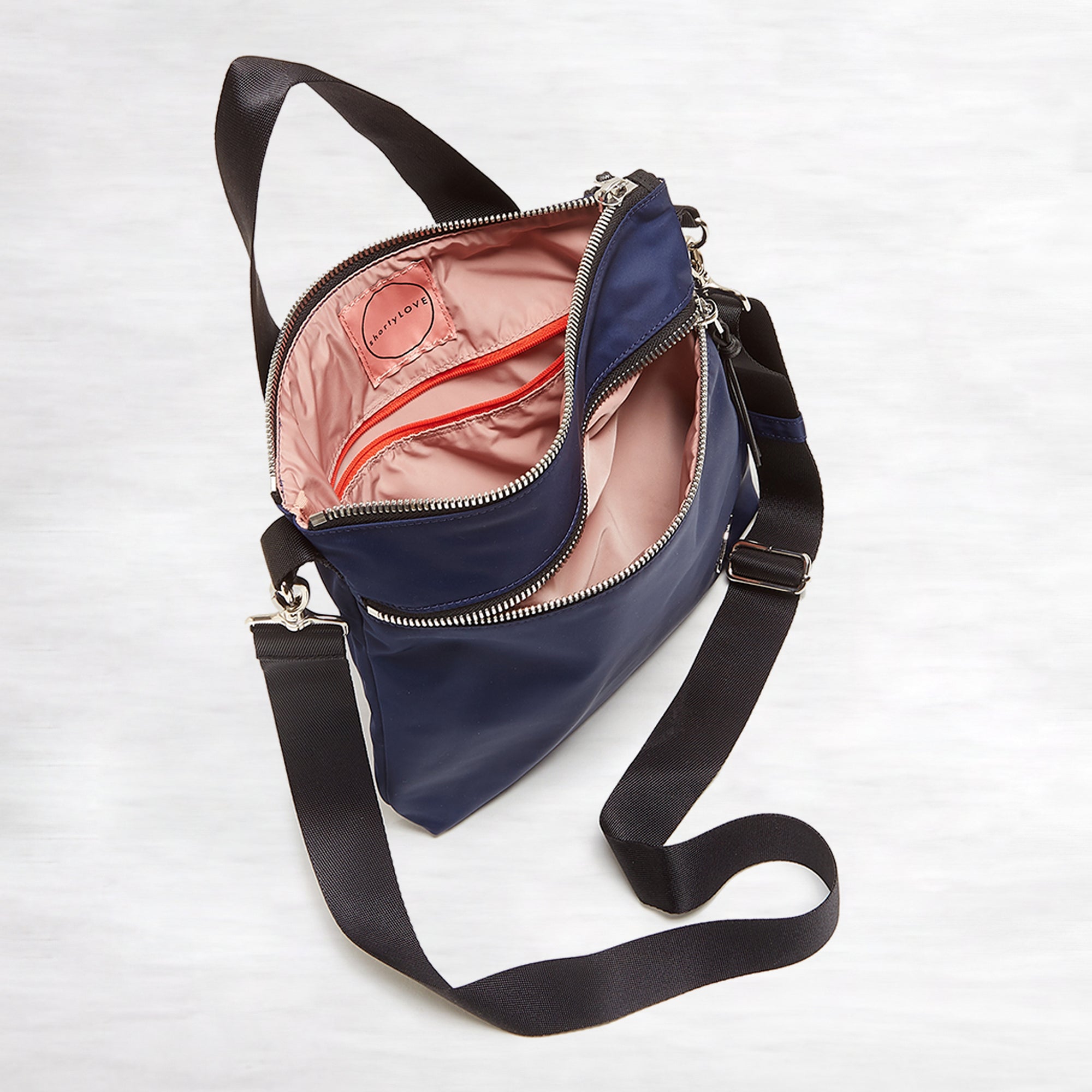 shortyLOVE amuse medium sized crossbody bag in navy; top-down view showing interior pink lining against white background.