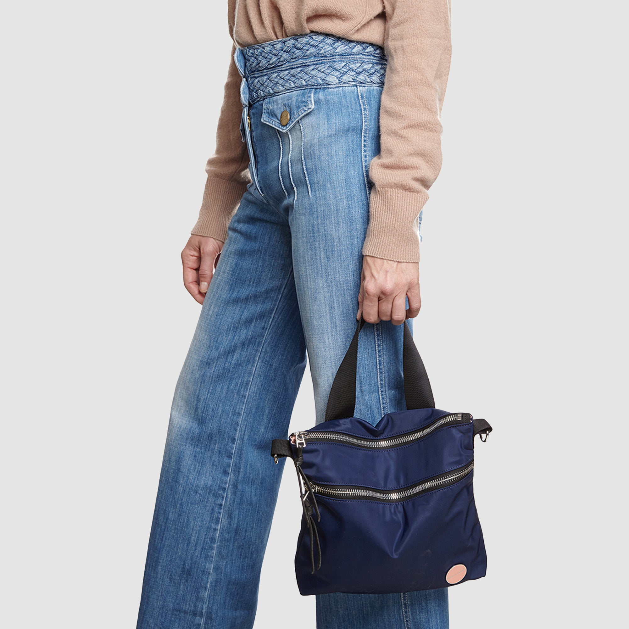 shortyLOVE amuse medium sized crossbody bag in navy; on model in tan v-neck long sleeve sweater and jeans against white background.