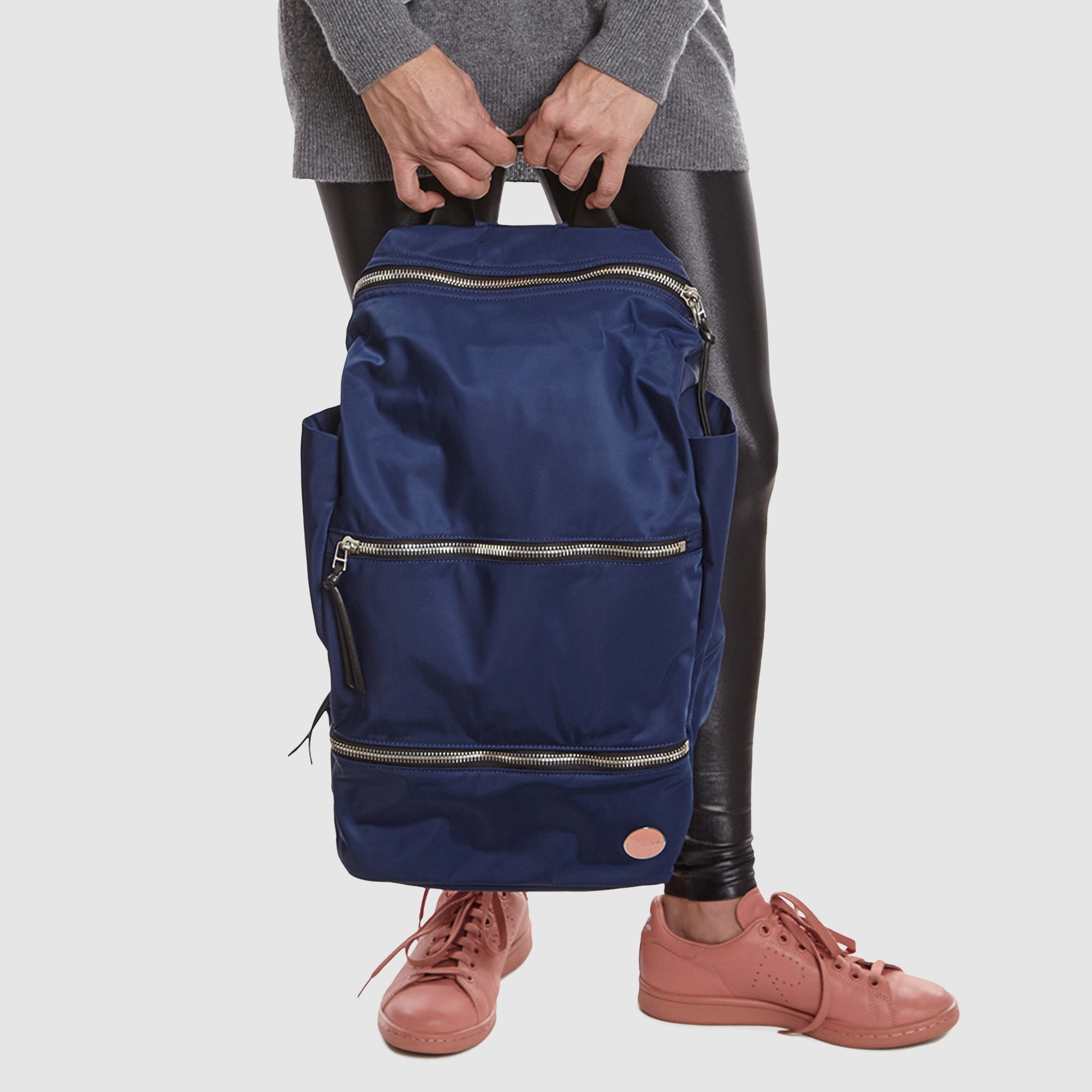 Person holding a navy blue boxer backpack on a plain background