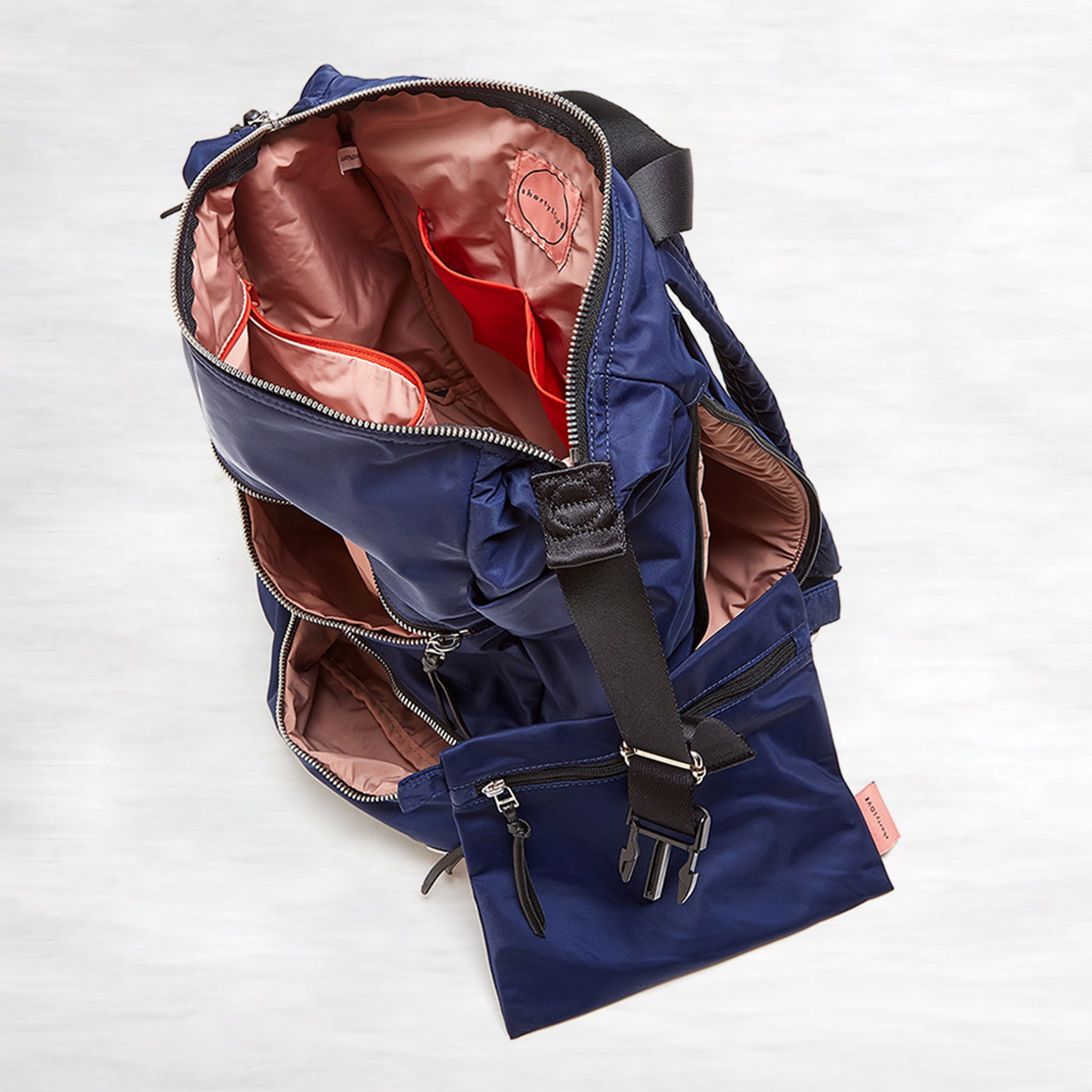 shortyLOVE boxer backpack bag in navy; top-down view showing interior pink lining against white background.