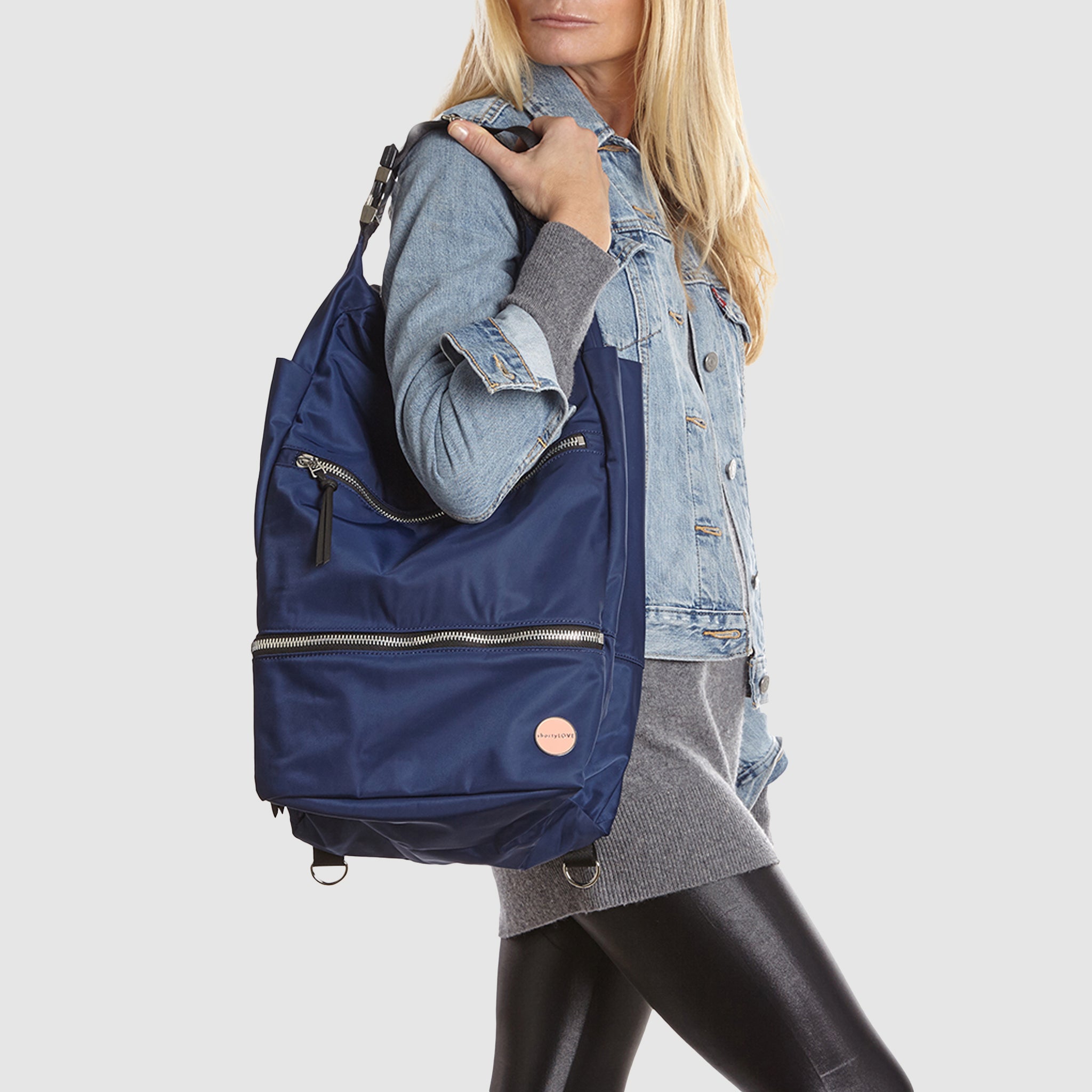 Woman holding a navy blue boxer backpack against a light gray background
