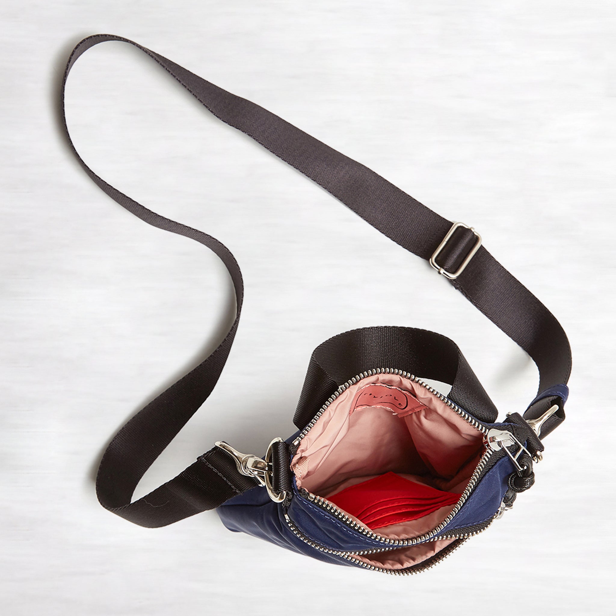 shortyLOVE shorthand crossbody phone bag in navy; top-down view showing interior pink lining against white background.