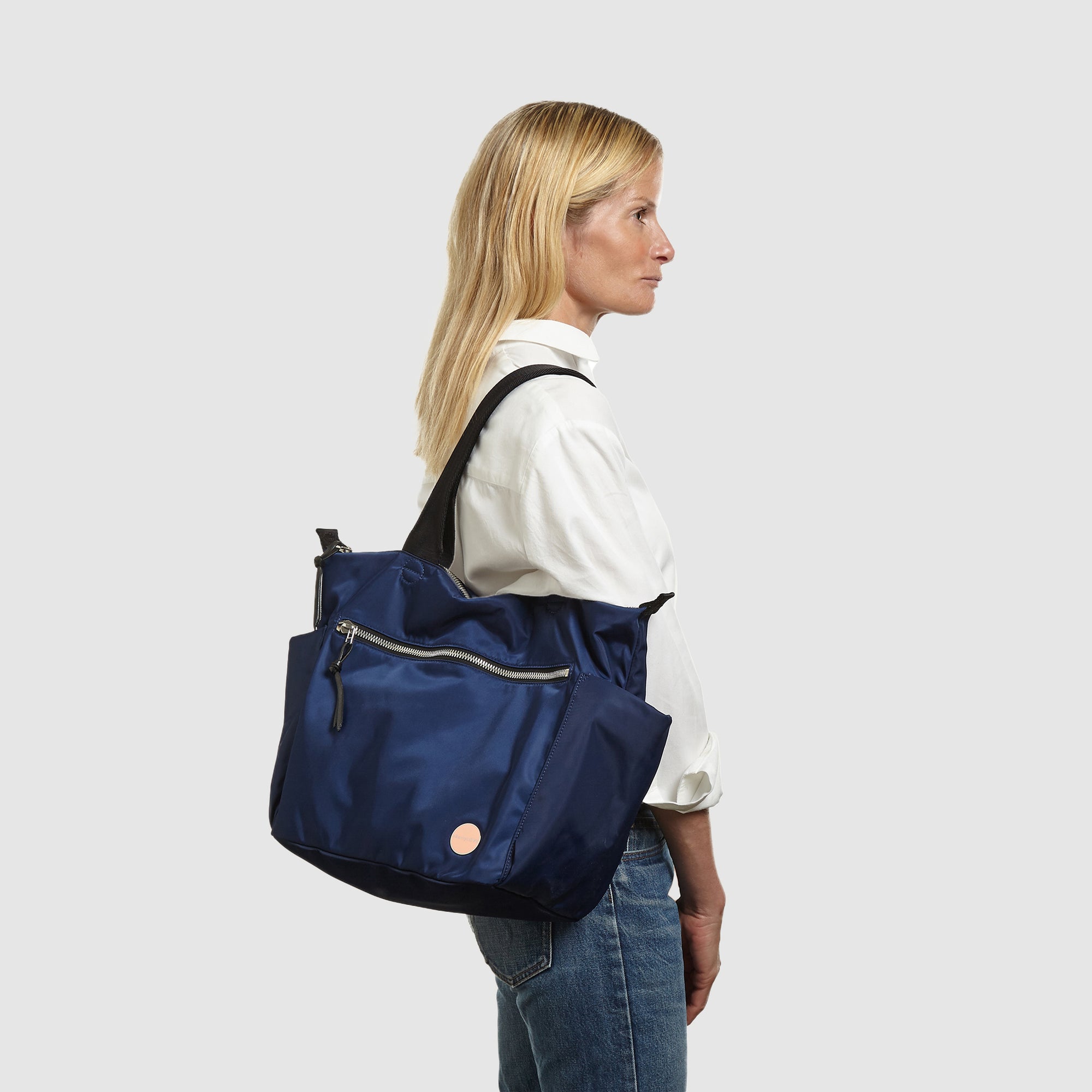 shortyLOVE tillie tote bag in navy; on model in white button down shirt and jeans against white background.