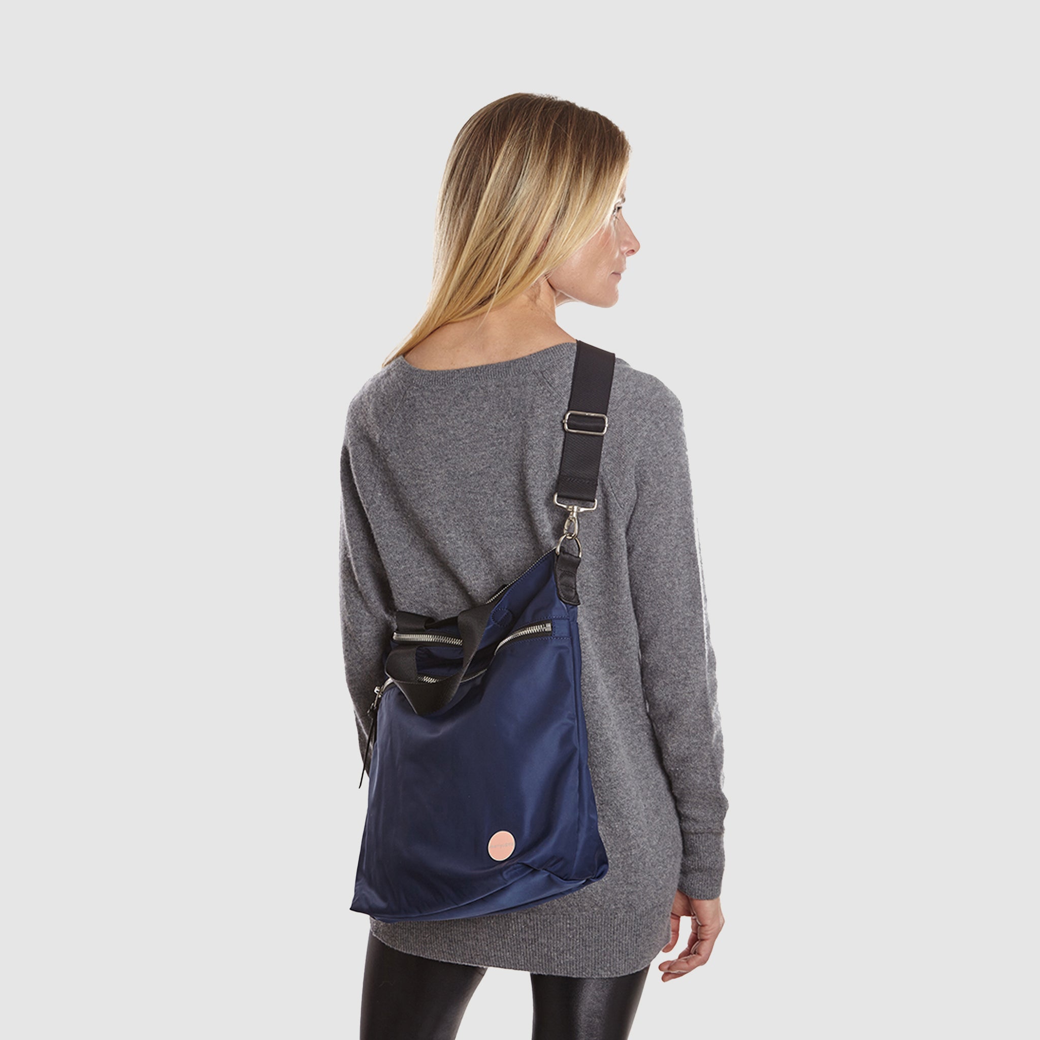 shortyLOVE wonder large crossbody/messenger bag in navy; on model in grey long sleeve sweater and black leggings against white background.