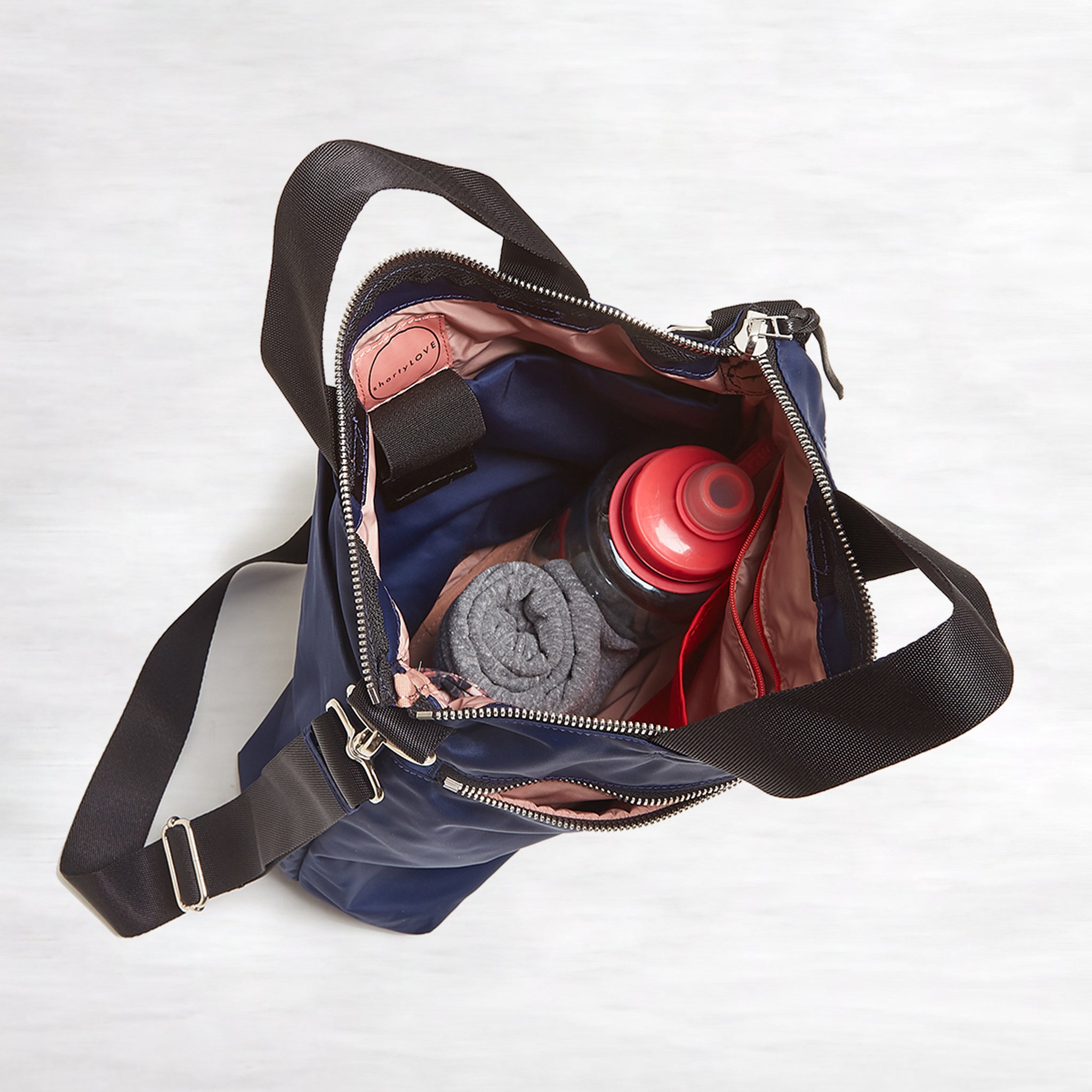 shortyLOVE wonder large crossbody/messenger bag in navy; top-down view showing interior pink lining against white background.