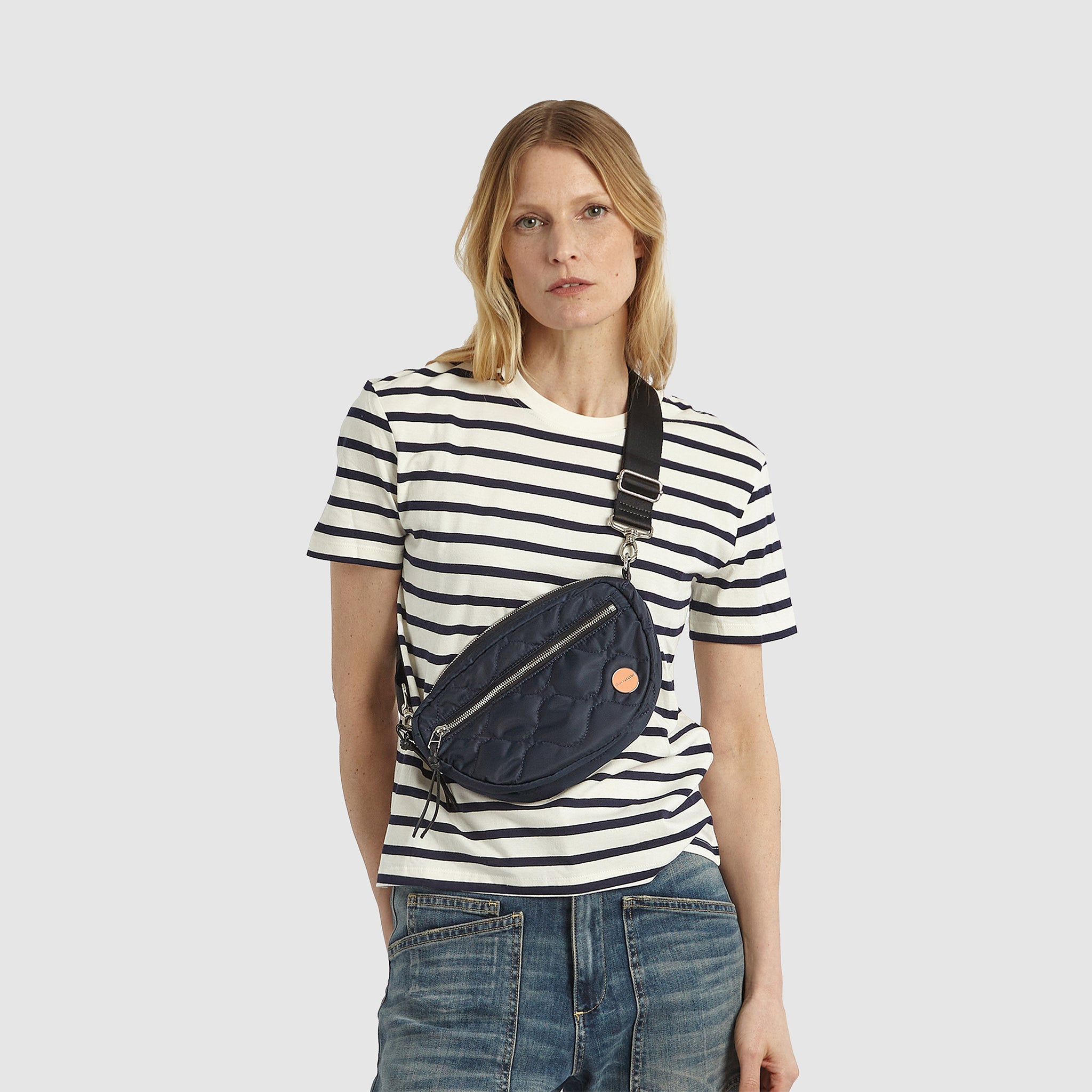 shortyLOVE small cruiser small crossbody bag in midnight; on model in white striped  shirt and jeans against white background.