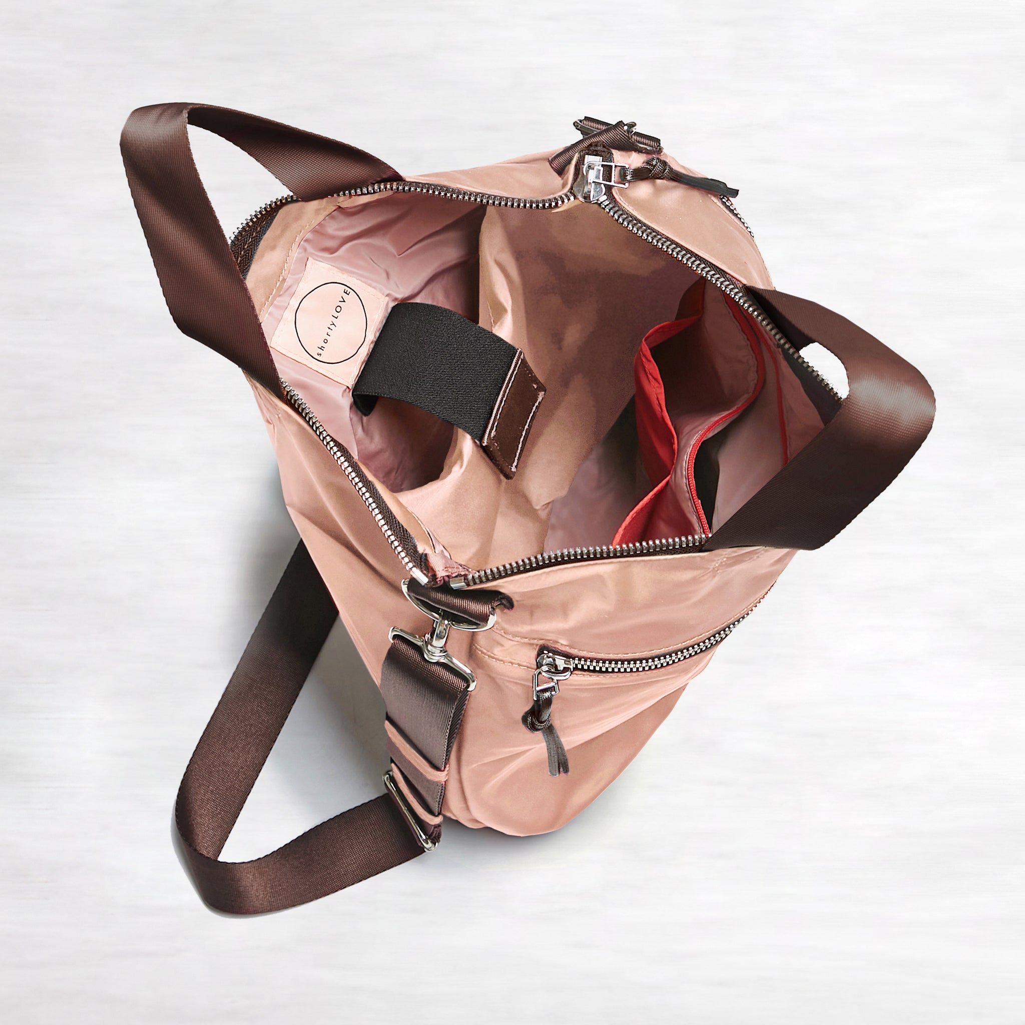 shortyLOVE wonder large crossbody/messenger bag in dusty peach; top-down view showing interior blush/red lining against white background.