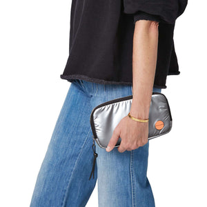 shortyLOVE jetty clutch/wallet in silver; hand held by model in black sweatshirt and jeans against white background.