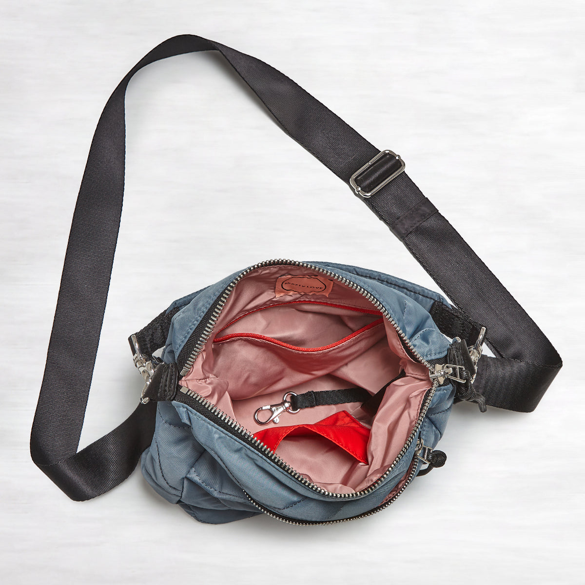 shortyLOVE marcel crossbody bucket bag in steel blue; top-down view showing interior blush lining against white background.