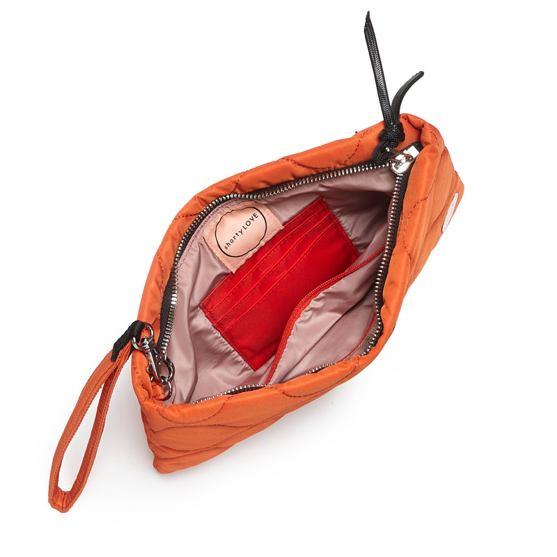 shortyLOVE cleo wristlet clutch in orange; top-down view showing interior blush lining against white background.