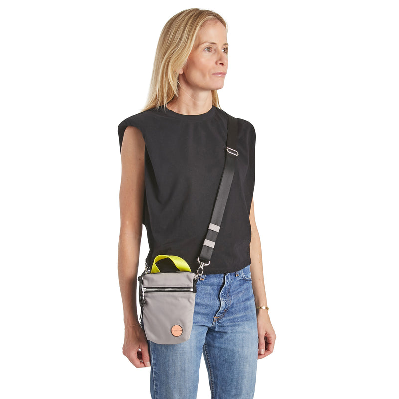 shortyLOVE shorthand small crossbody bag in grey; on model in black t-shirt and jeans against white background.