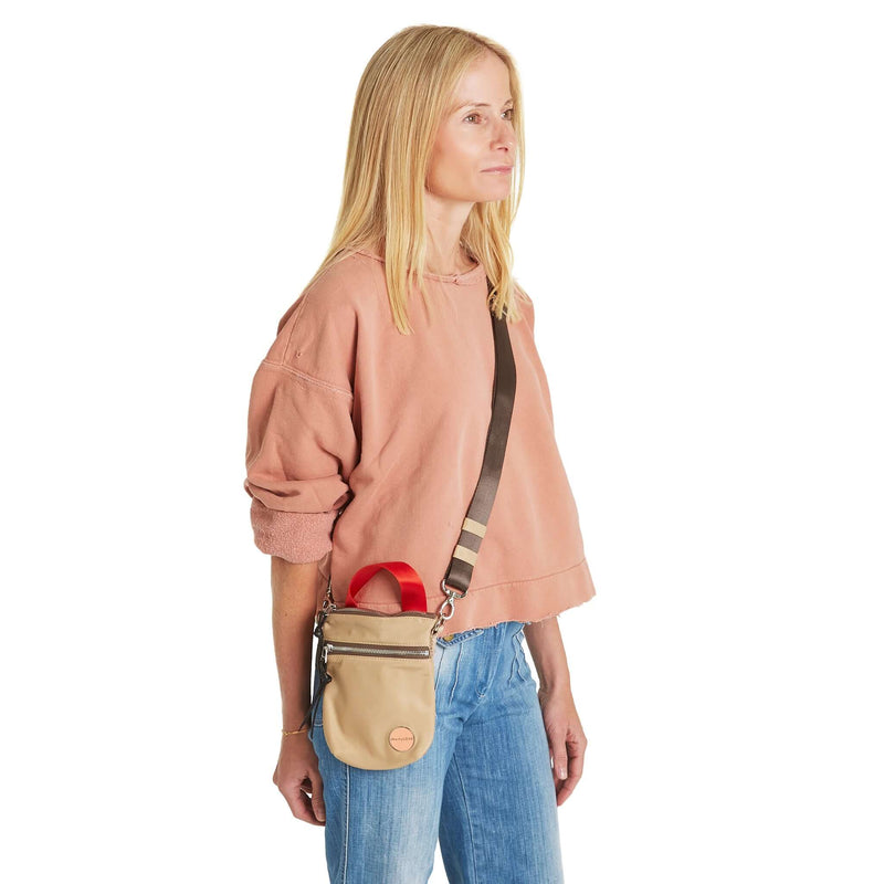 shortyLOVE shorthand small crossbody bag in khaki; on model in peach sweatshirt and jeans against white background.