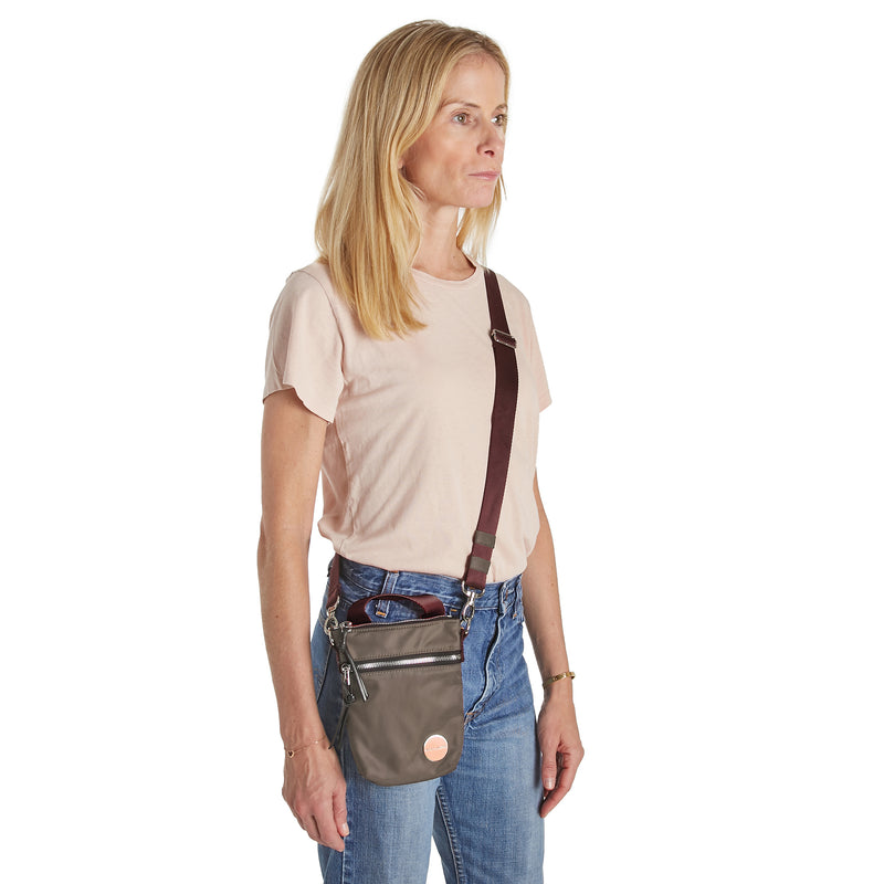 shortyLOVE shorthand small crossbody bag in mocha; on model in peach t-shirt and jeans against white background.