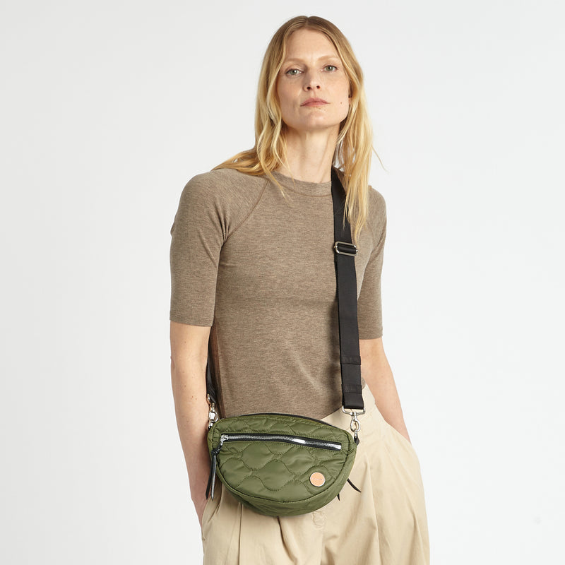 shortyLOVE small cruiser small crossbody bag in sage; on model in a tan top and pants against white background.