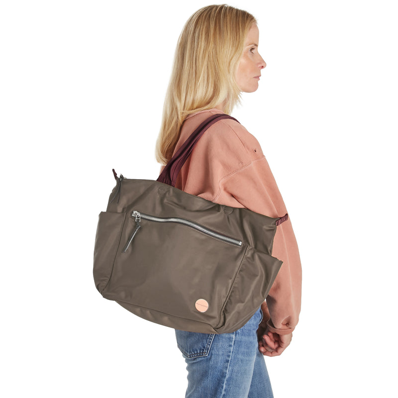 shortyLOVE tillie tote bag in mocha; on model in peach sweatshirt and jeans against white background.