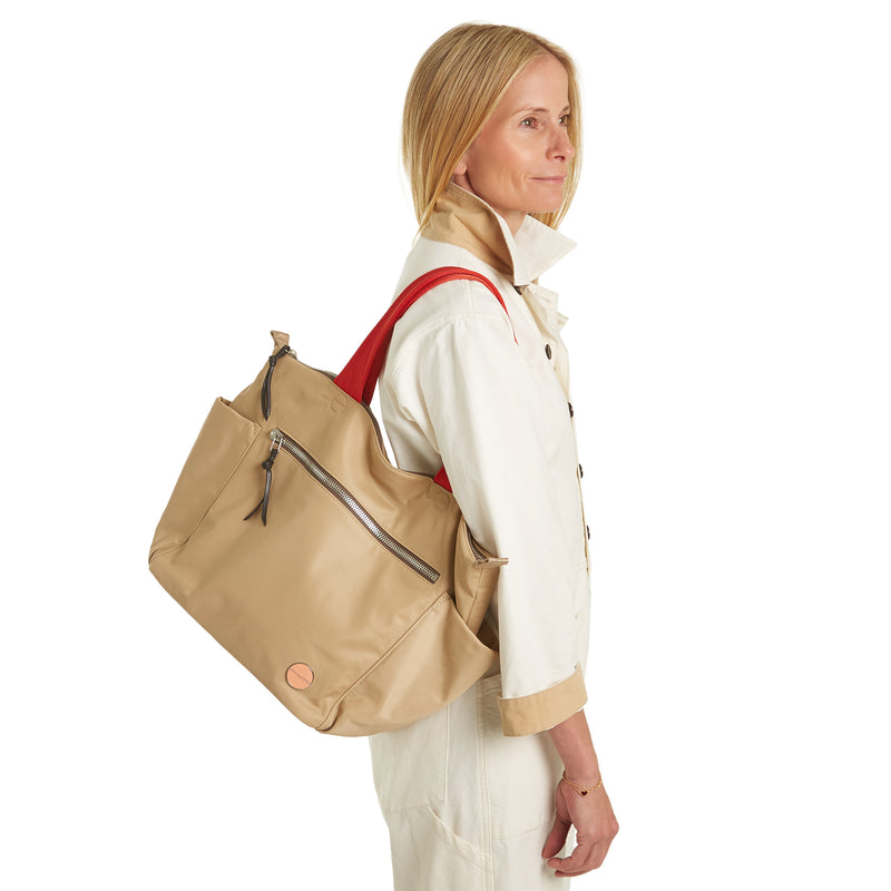 shortyLOVE tillie tote bag in khaki; on model in white jump suit against white background.