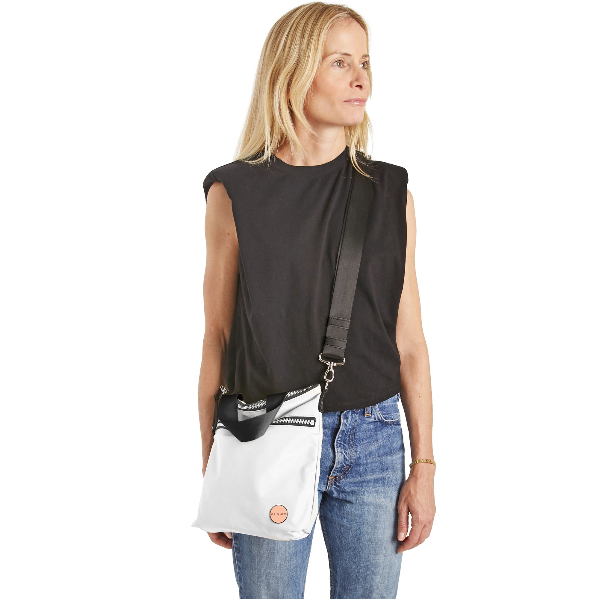 shortyLOVE amuse medium sized crossbody bag in white; on model in charcoal top and jeans against white background.