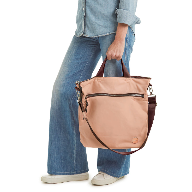 shortyLOVE wonder large crossbody/messenger bag in dusty peach; hand held by model in jeans against white background.