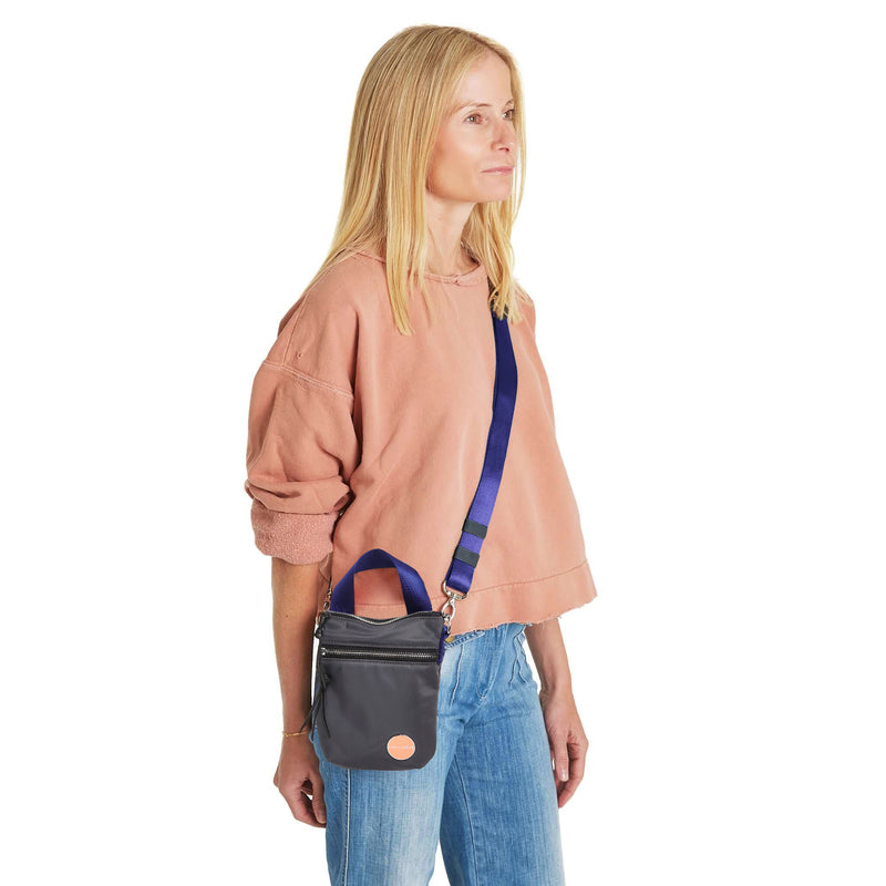 shortyLOVE shorthand small crossbody bag in charcoal; on model in peach sweatshirt and jeans against white background.