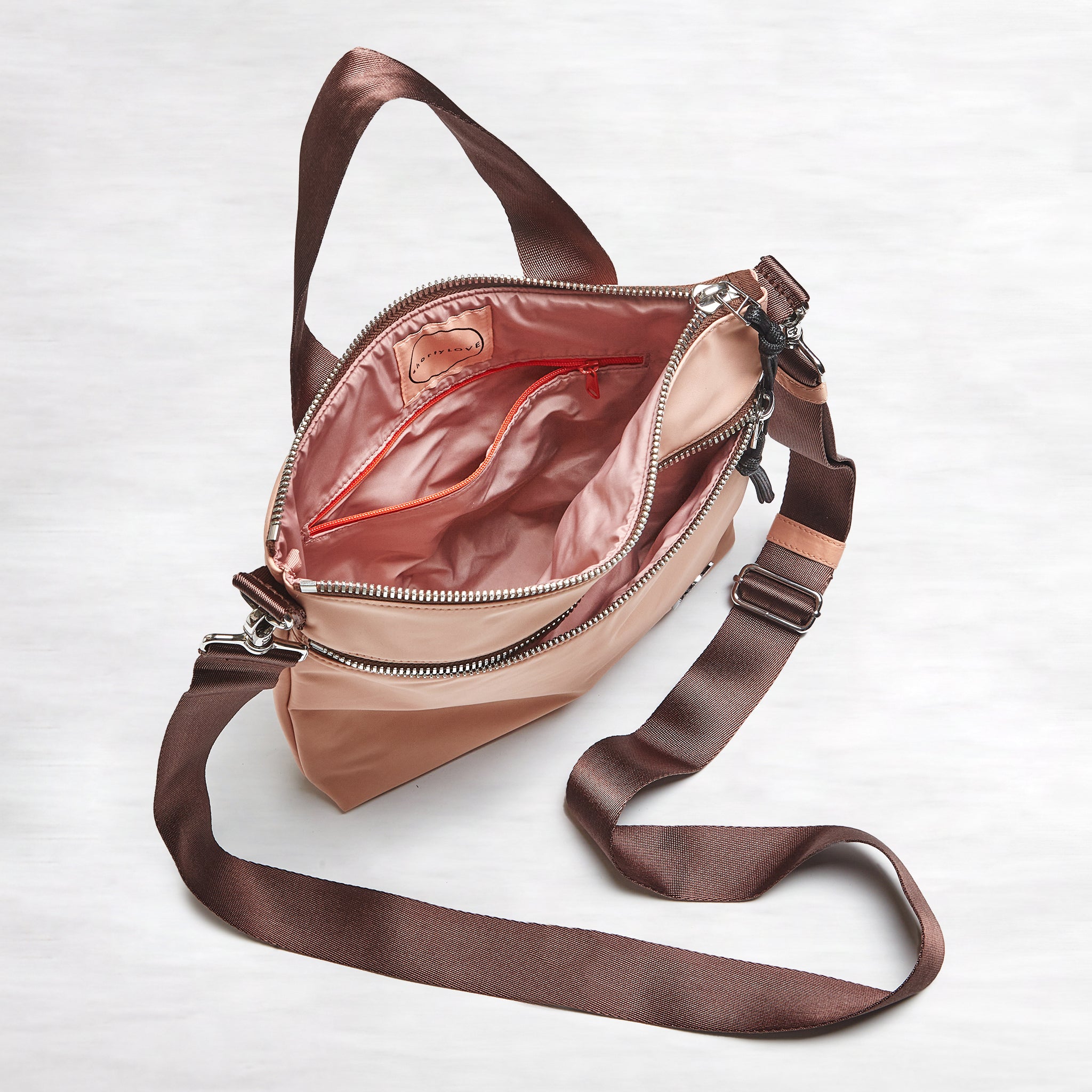 shortyLOVE amuse medium sized crossbody bag in dusty peach; top down open view against grey background.