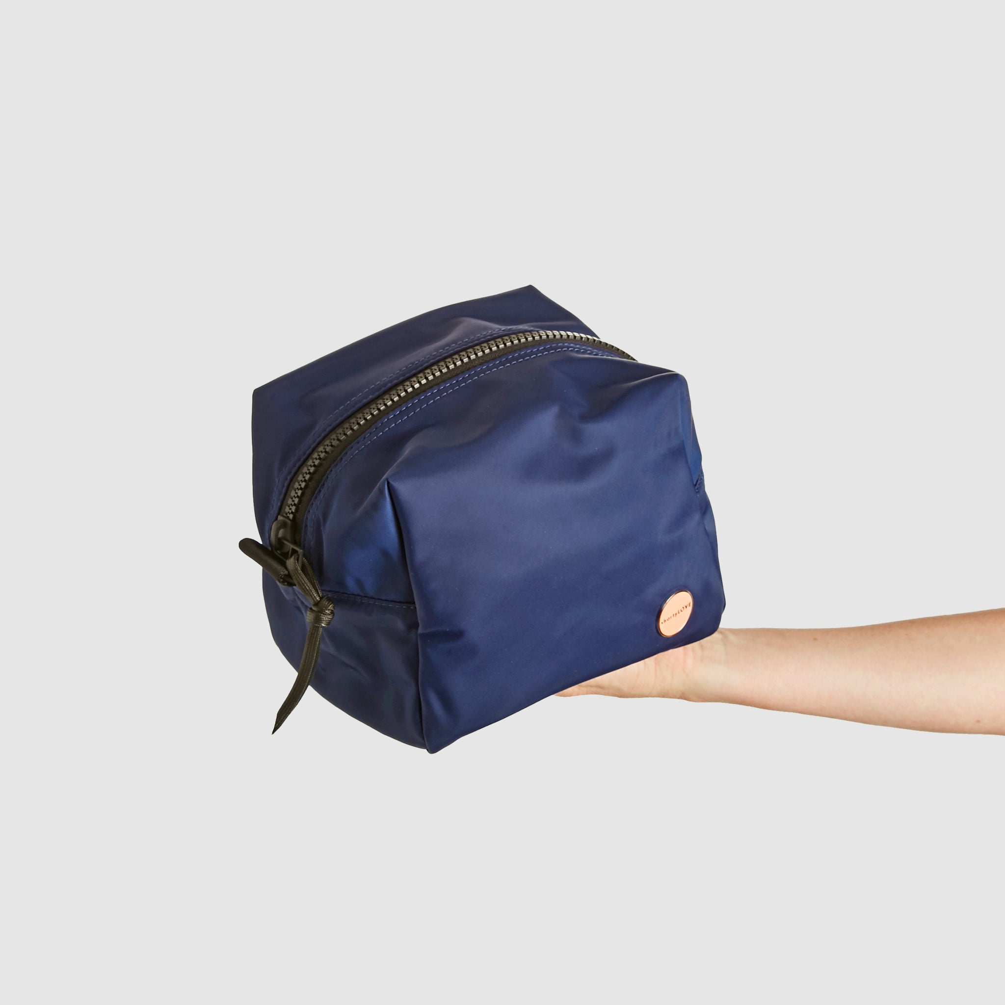 shortyLOVE stevie cosmetic bag in navy; hand held by model.