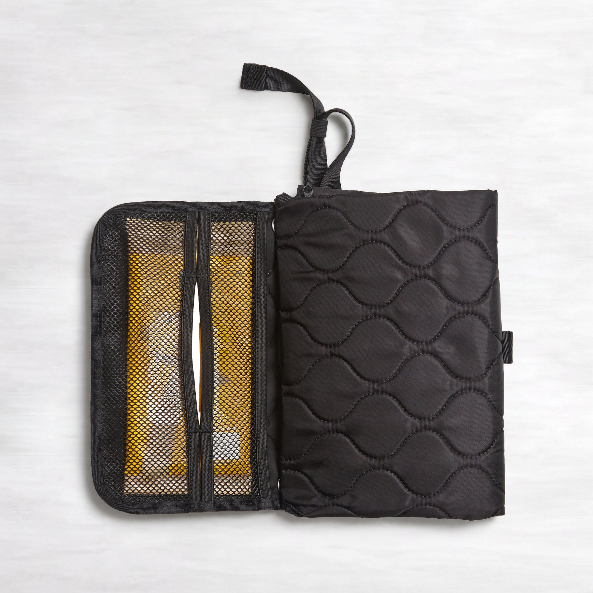 Black quilted diaper changing mat partially opened - top-down view on a white background