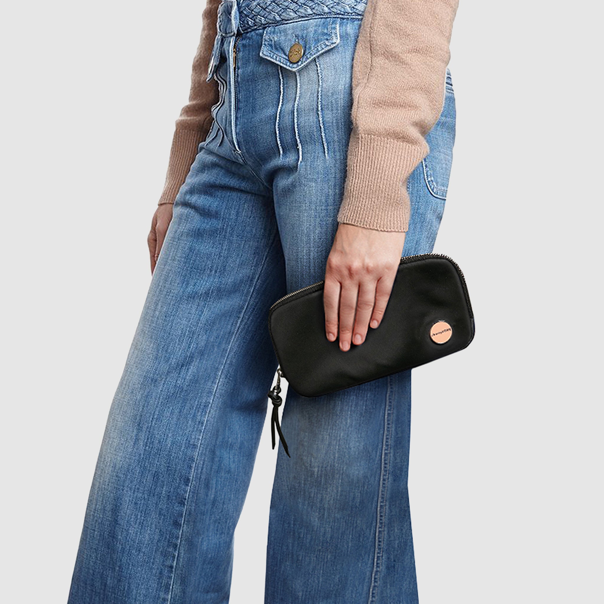 shortyLOVE jetty clutch/wallet in black; hand held by model in tan sweater and jeans against white background.
