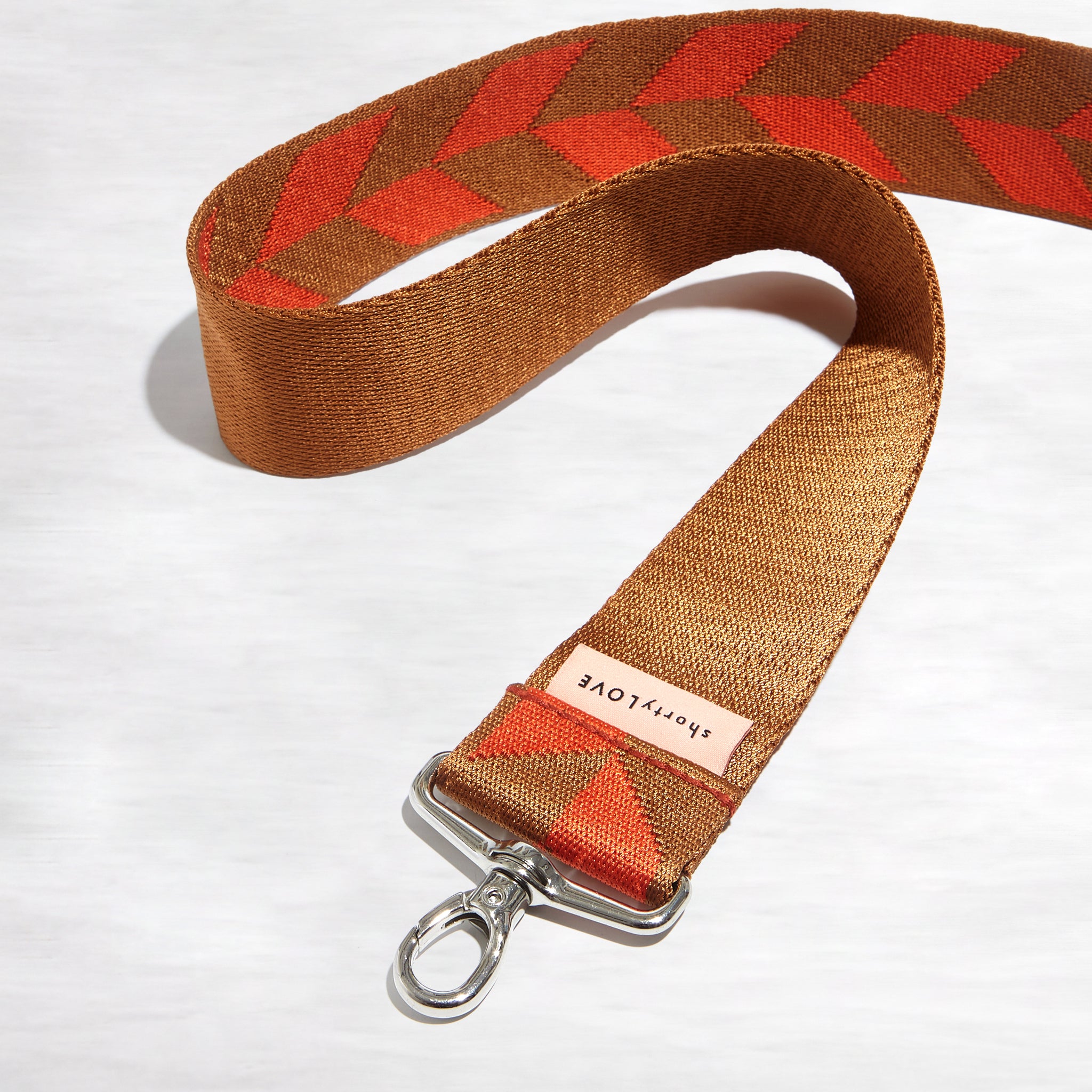 shortyLOVE boardwalk strap in arrow design orange/tobacco; snaking against white background.