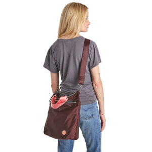 shortyLOVE wonder large crossbody/messenger bag in burgundy; on model in grey t-shirt and jeans against white background.