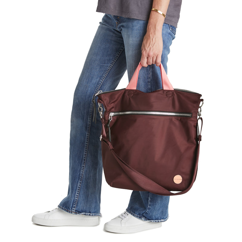 shortyLOVE wonder large crossbody/messenger bag in burgundy; hand held by model in jeans against white background.