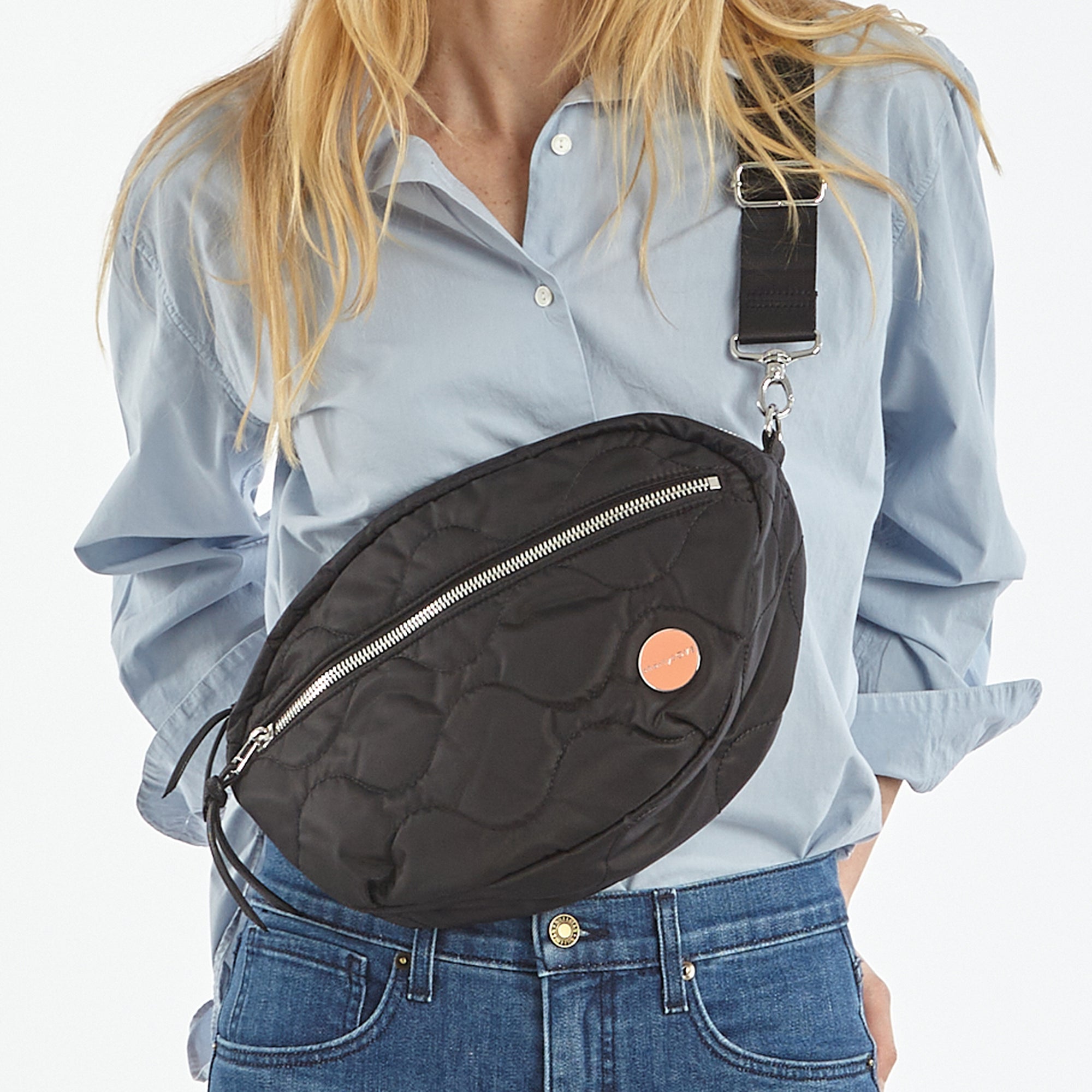 shortyLOVE cruiser medium crossbody bag in black; on model in blue button down shirt and jeans against white background.
