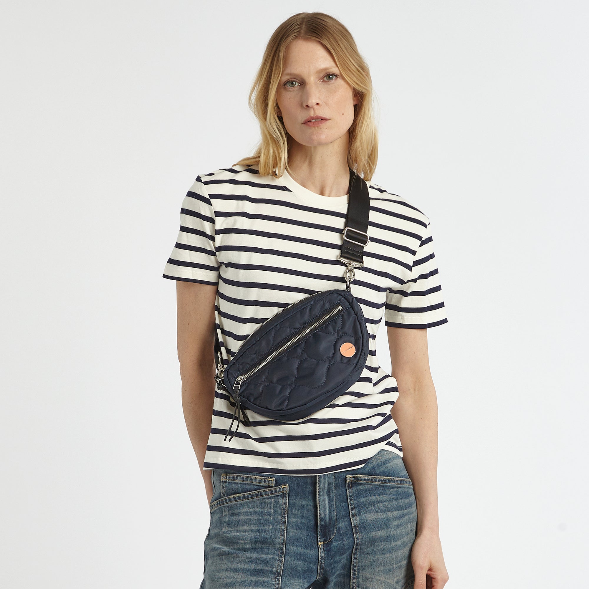 shortyLOVE small cruiser small crossbody bag in midnight; on model in white striped  shirt and jeans against white background.