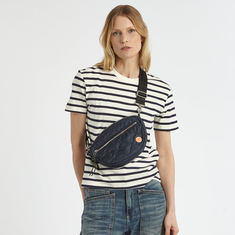 shortyLOVE small cruiser small crossbody bag in midnight; on model in white striped  shirt and jeans against white background.