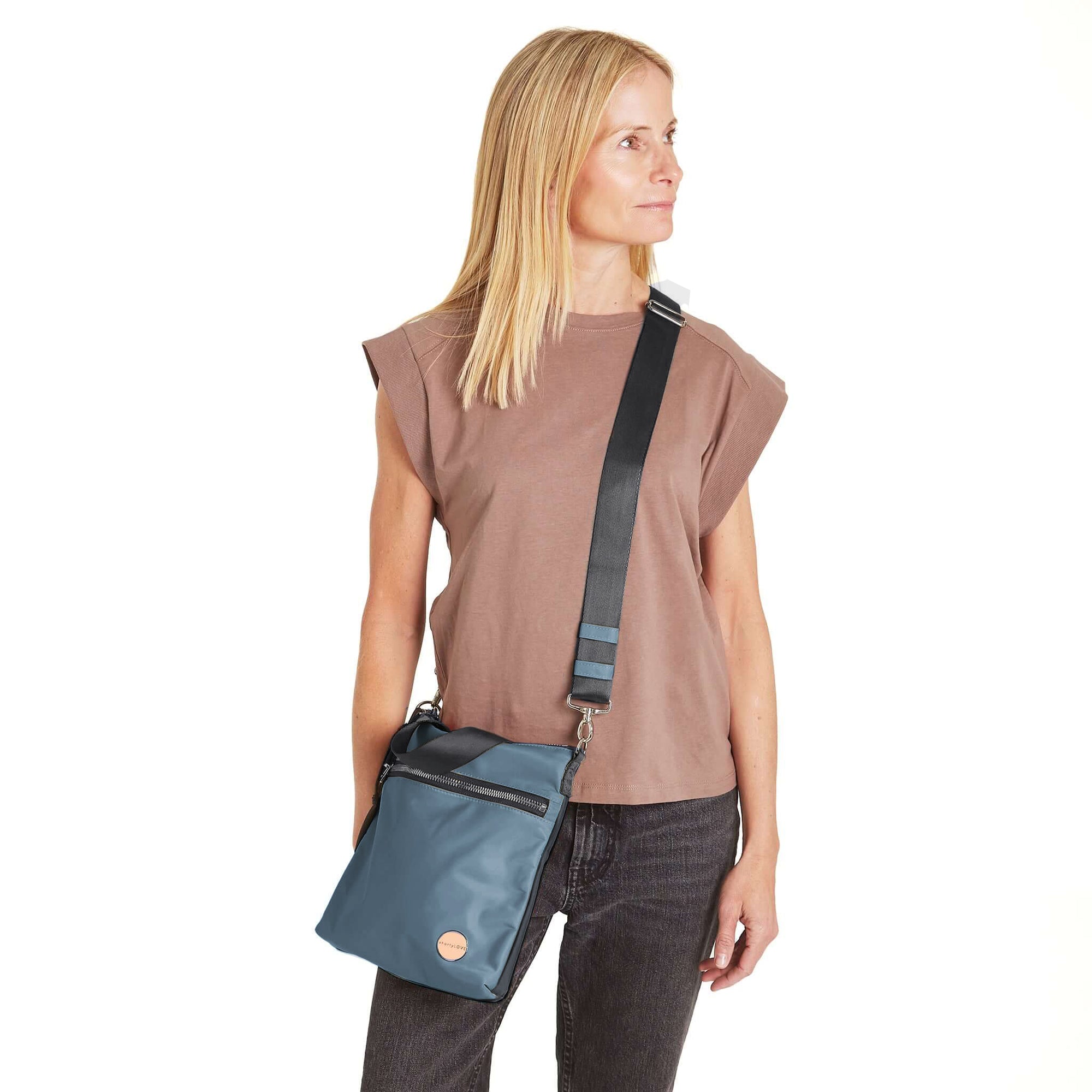 shortyLOVE amuse medium sized crossbody bag in steel blue/charcoal; on model in blush rose top and jeans against white background.