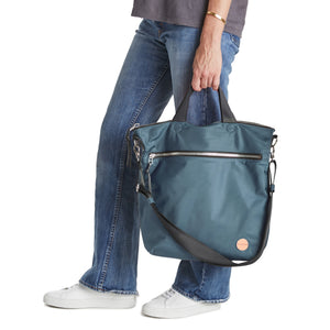 shortyLOVE wonder large crossbody/messenger bag in steel blue/charcoal; hand held by model in jeans against white background.