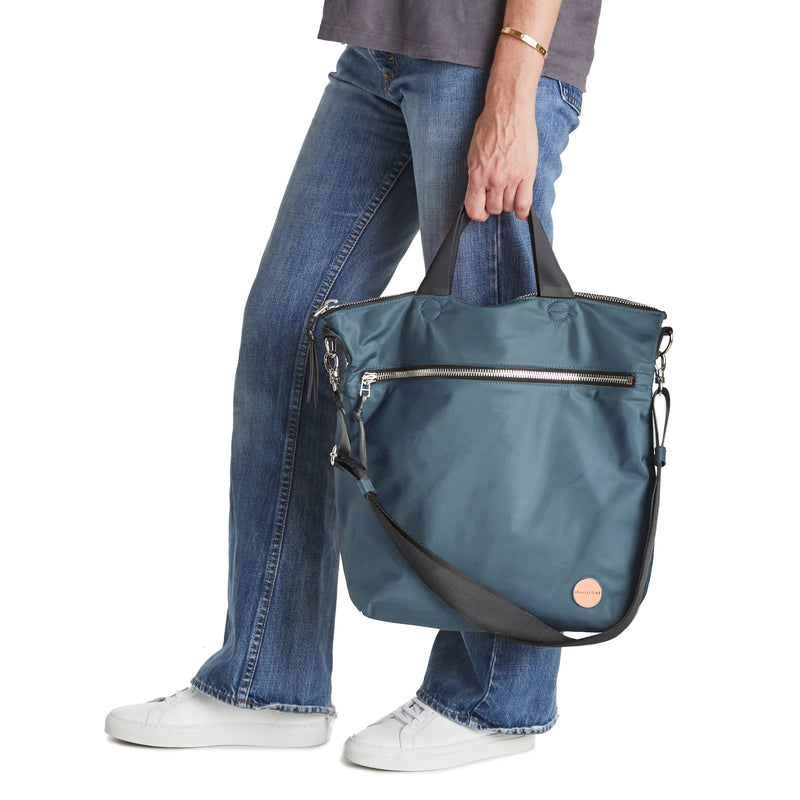 shortyLOVE wonder large crossbody/messenger bag in steel blue/charcoal; hand held by model in jeans against white background.