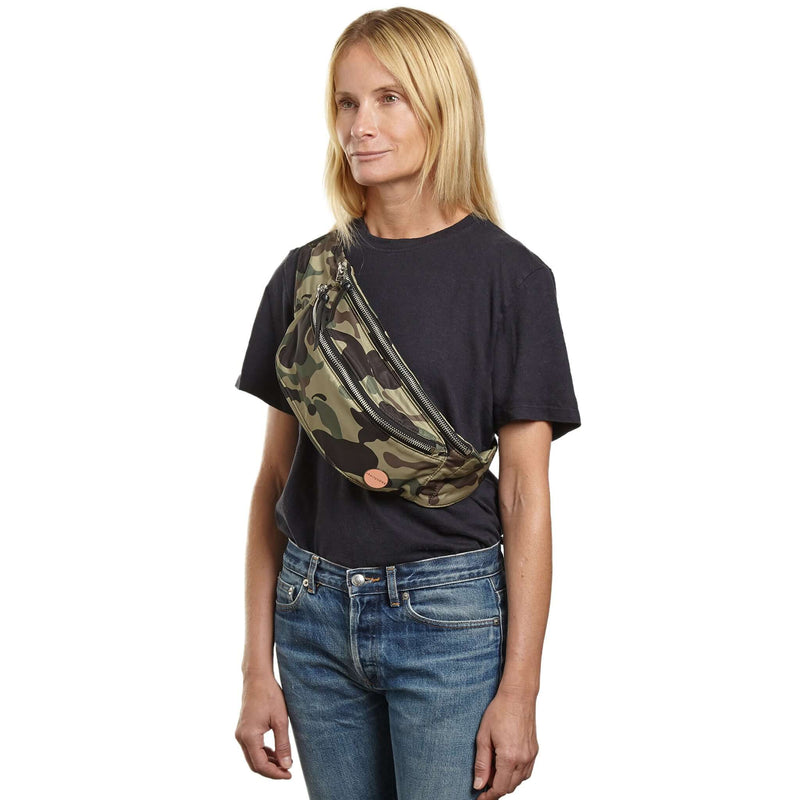 shortyLOVE arcade belt bag in green camo; on model in black t-shirt and jeans against white background.