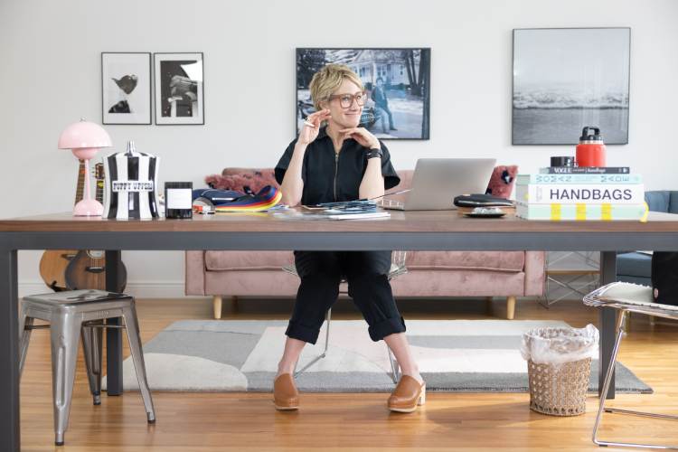 sloane in black jumpsuit sitting at office desk