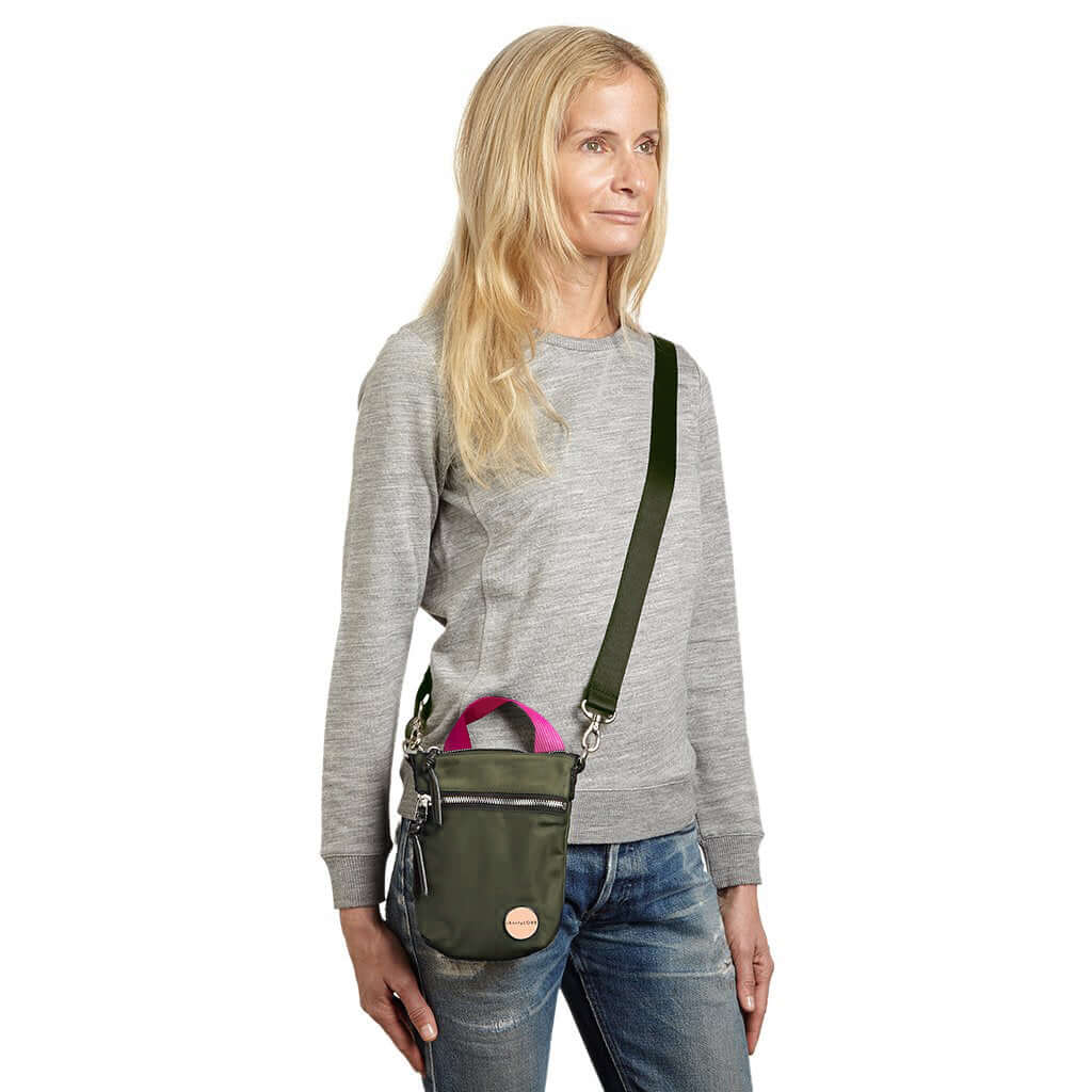 shortyLOVE shorthand crossbody phone bag in army green; on model in grey sweatshirt and jeans against white background.
