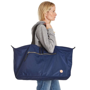 shortyLOVE friday weekender travel bag in navy; on model in grey hooded sweatshirt and jeans against white background.