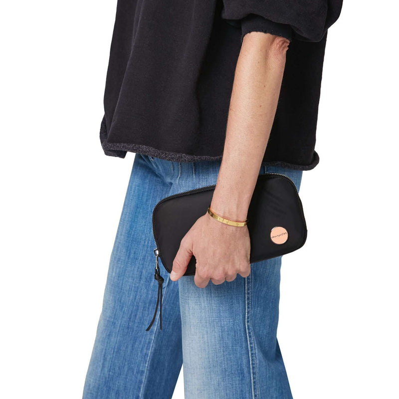shortyLOVE jetty clutch/wallet in black; hand held by model in black sweatshirt and jeans against white background.