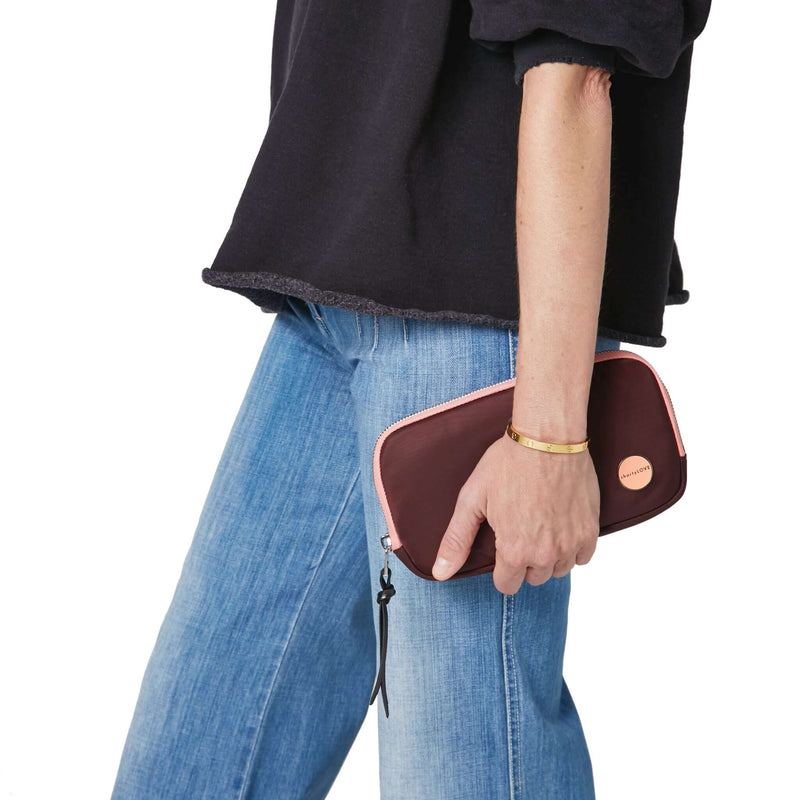 shortyLOVE jetty clutch/wallet in burgundy; hand held by model in black sweatshirt and jeans against white background.