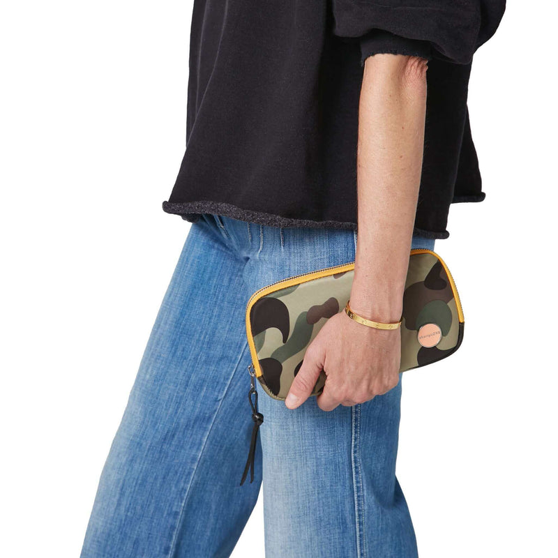 shortyLOVE jetty clutch/wallet in green camo; hand held by model in black sweatshirt and jeans against white background.
